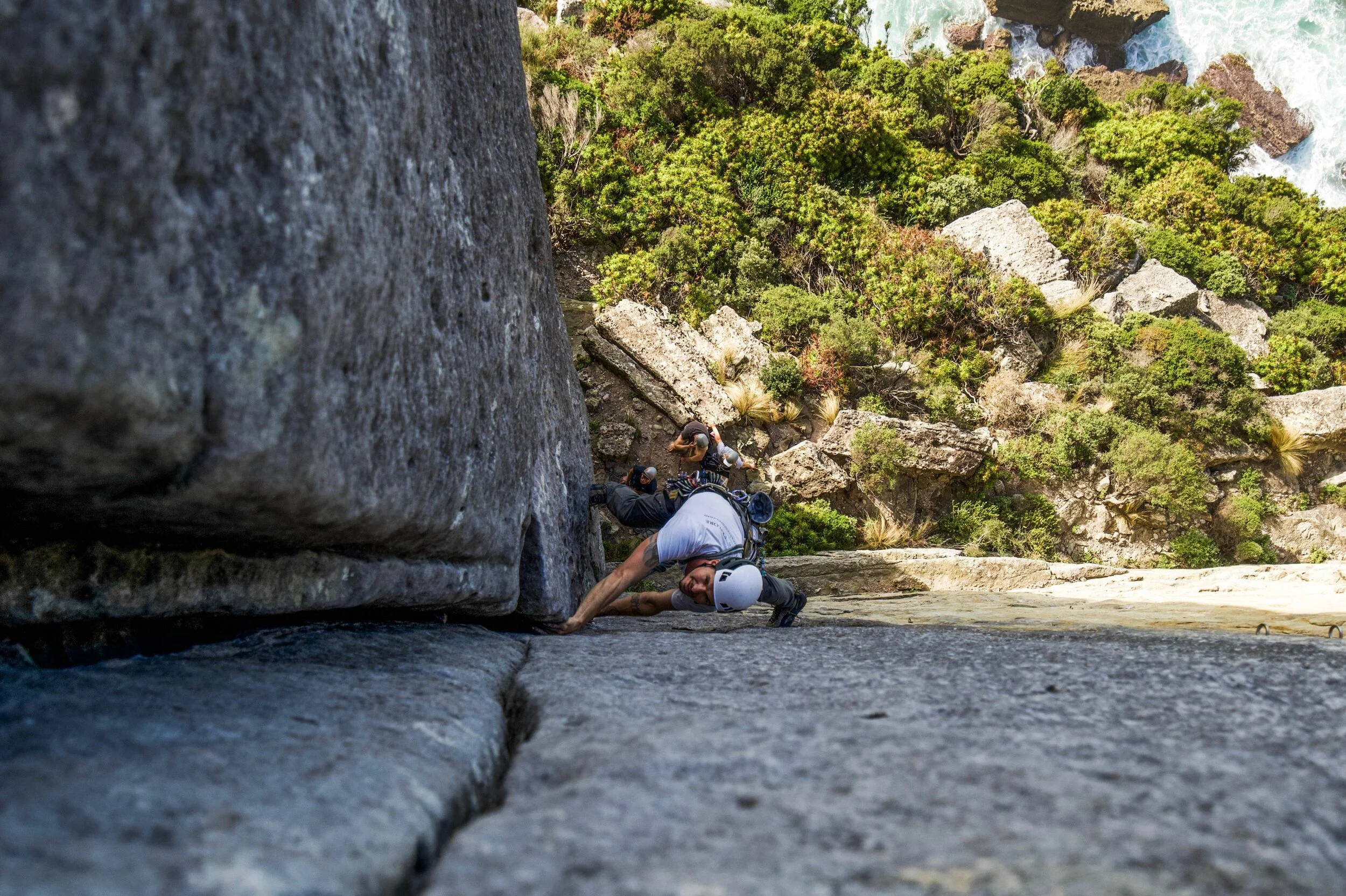 Qualified rock climbing guide demonstrates trad climbing techinques and provides instruction on a cliff in New South Wales