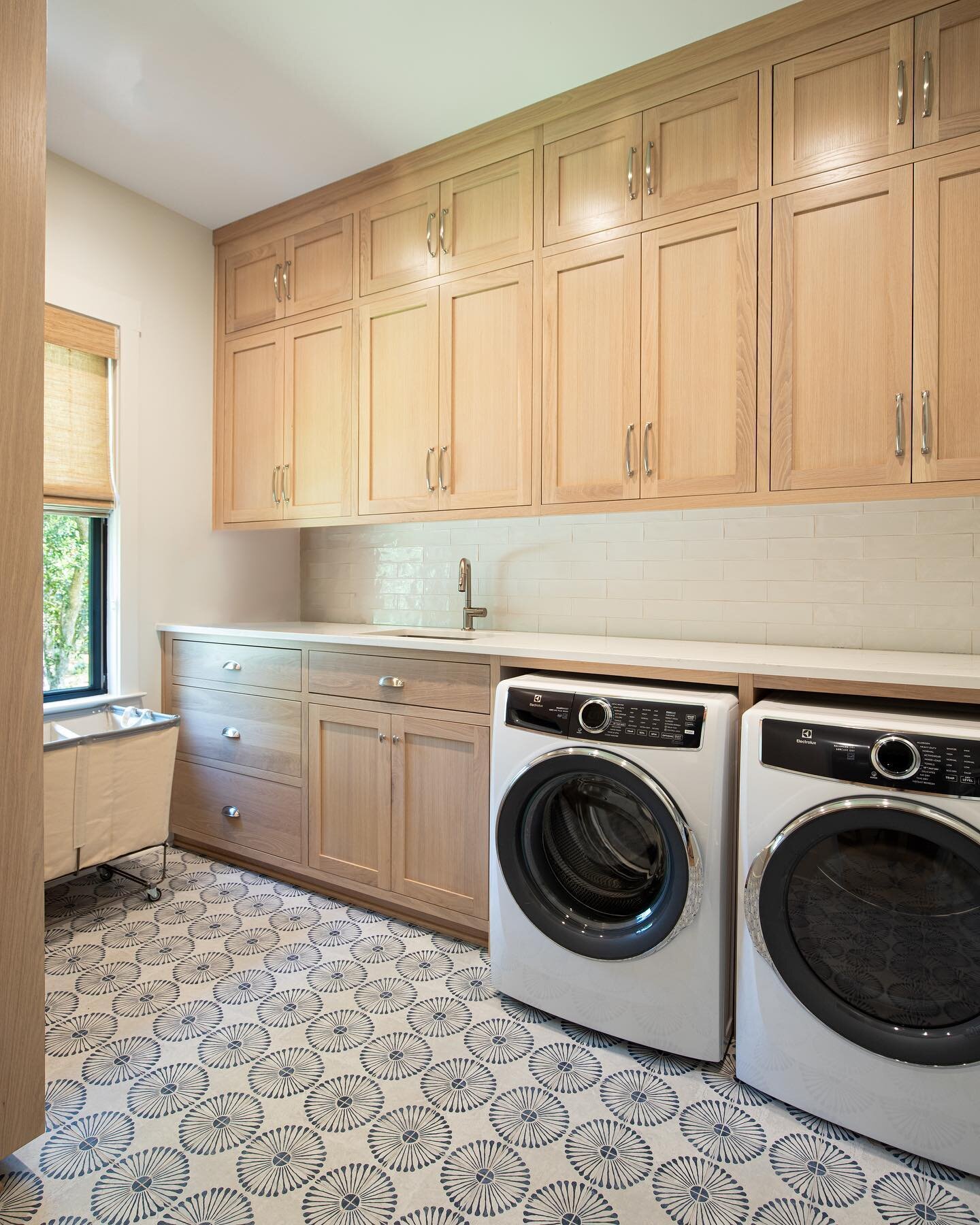 Laundry day just got a whole lot less boring 👀 The ceiling-high cabinetry in a light oak provides ample storage space, while the blue patterned tiles on the floor add a little color and personality to the space. While we can&rsquo;t actually make do