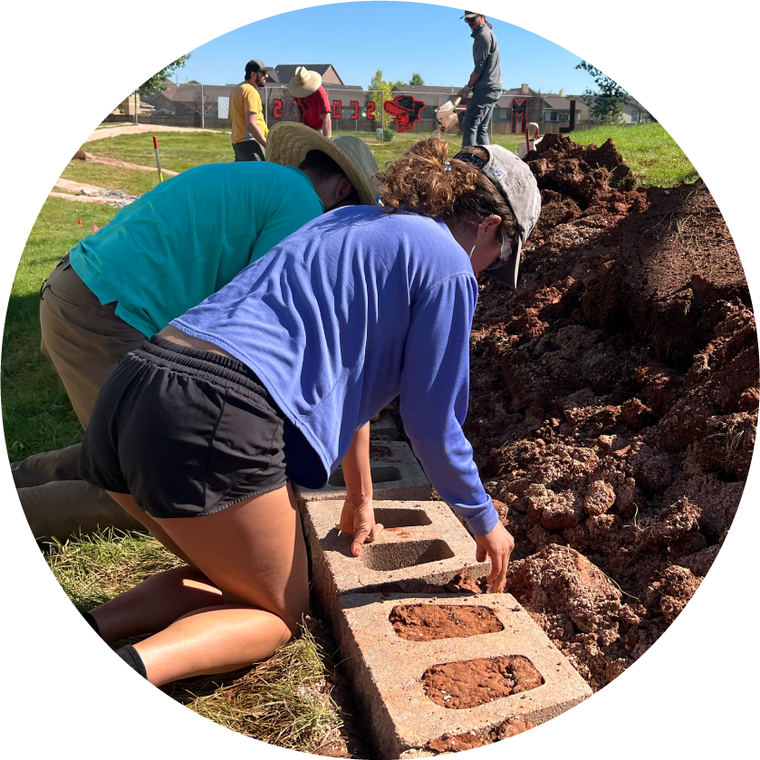 Two volunteers putting dirt inside bricks