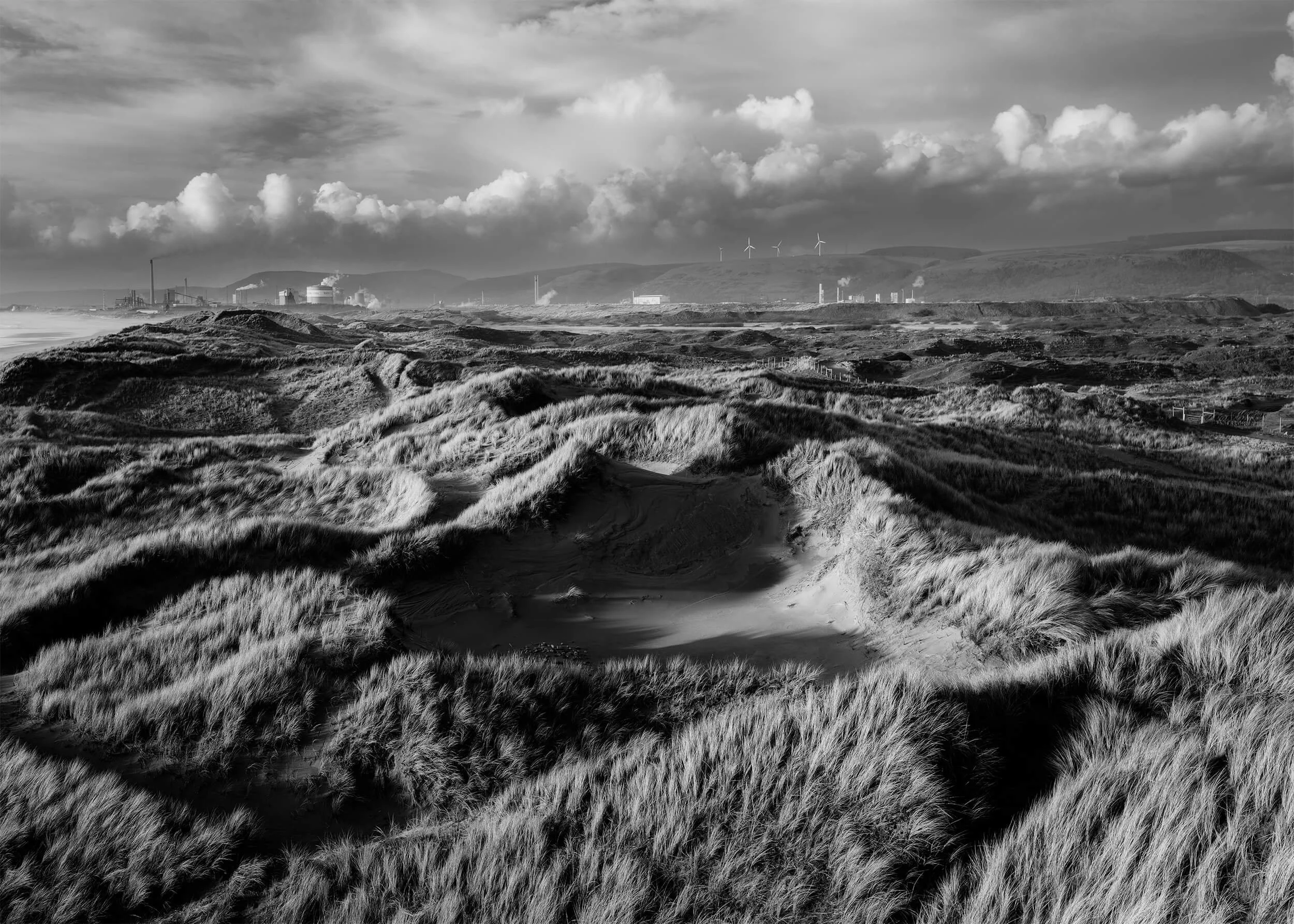 Black and white photo of the dunes at Sker beach looking toward Port Talbot Steel Works