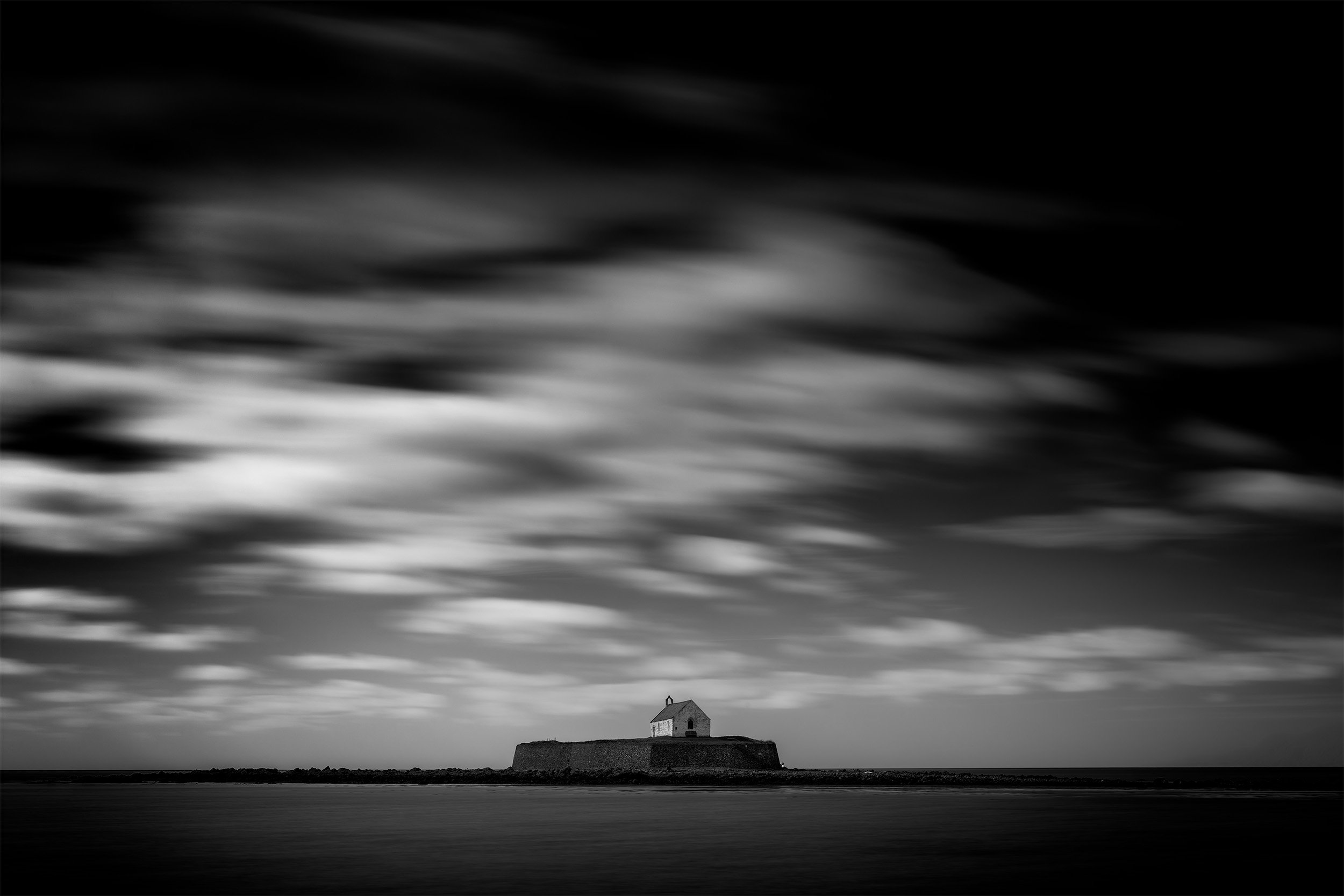 A fine art black and white long exposure of St Cwyfan’s Church, Anglesey — often called the “Church in the Sea.” Captured during calm coastal conditions, the image softens the sea and sky into a minimalist, dreamlike scene that reflects the church’s 