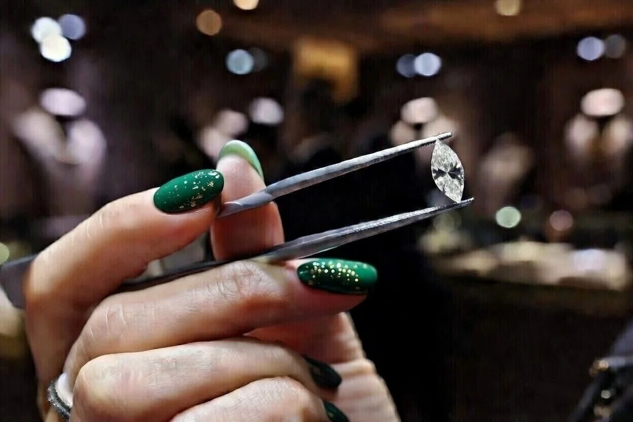 Stacks of 100-dollar bills, a glass of whiskey, a leather-bound notebook, a black box with diamonds, and a black notebook on a wooden table.