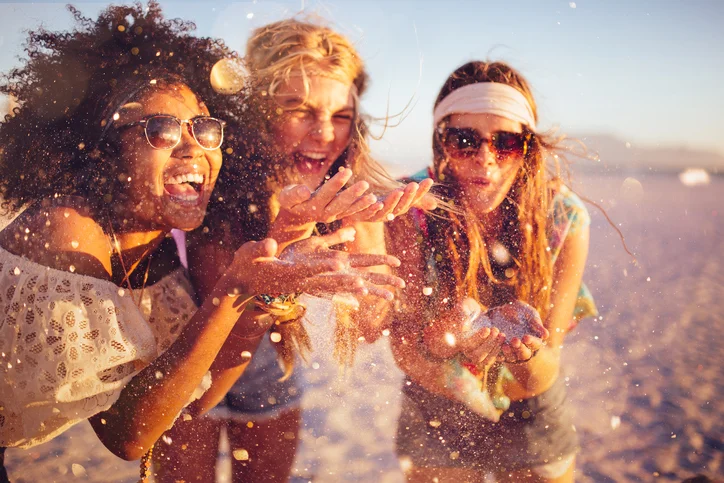 Girls-blowing-confetti-from-their-hands-on-a-beach-471881654_727x484.jpeg