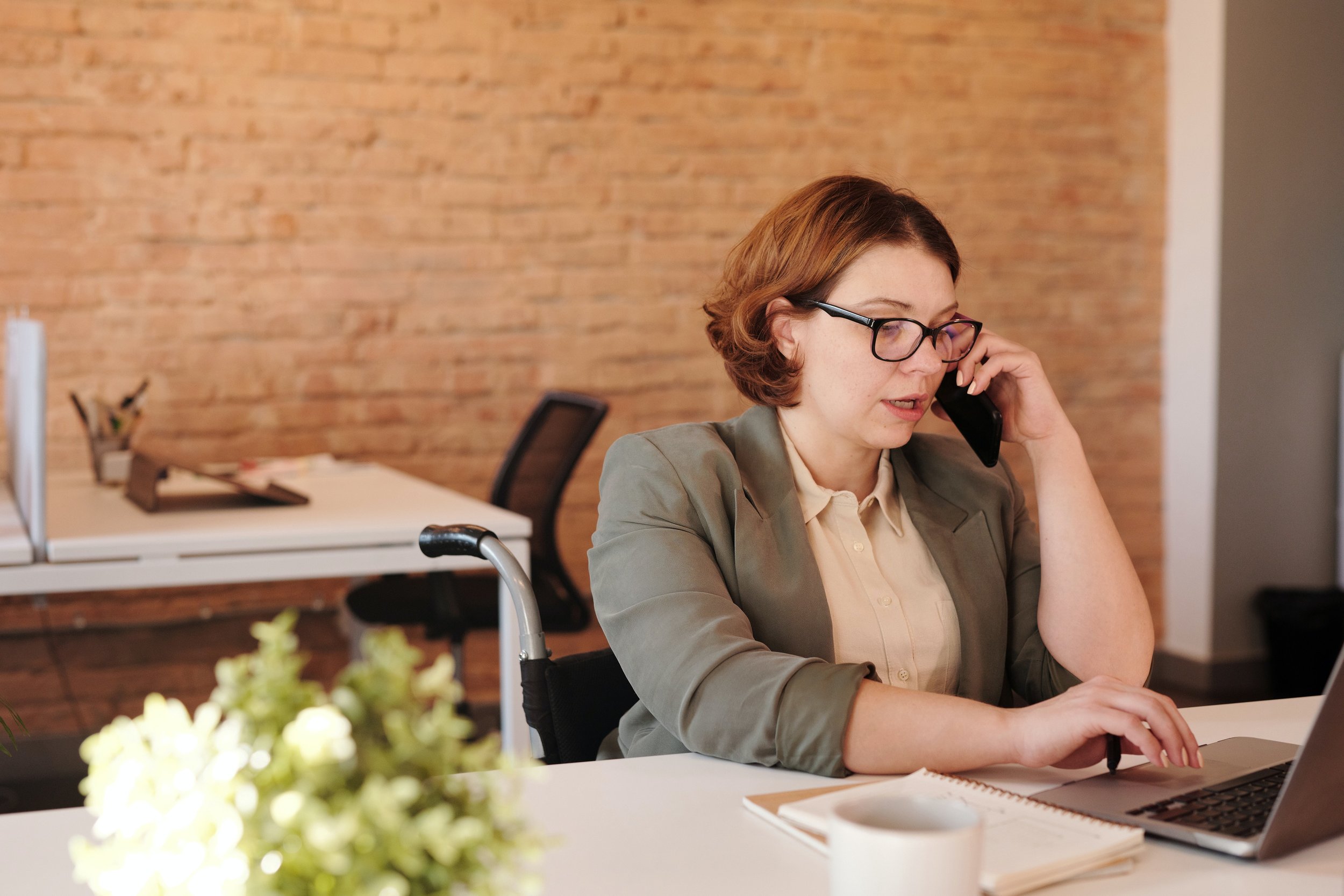 A young mother participates in a therapy session by phone from her desk at work.