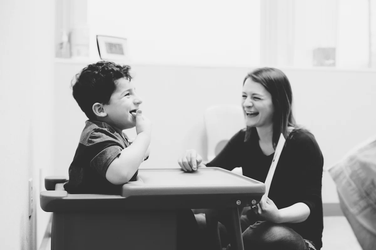 Boy and therapist laughing together at table blkwht.jpg