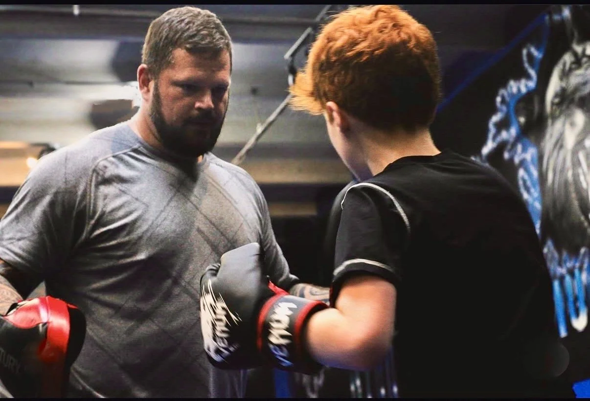 An adult holding kickboxing pads for a kid