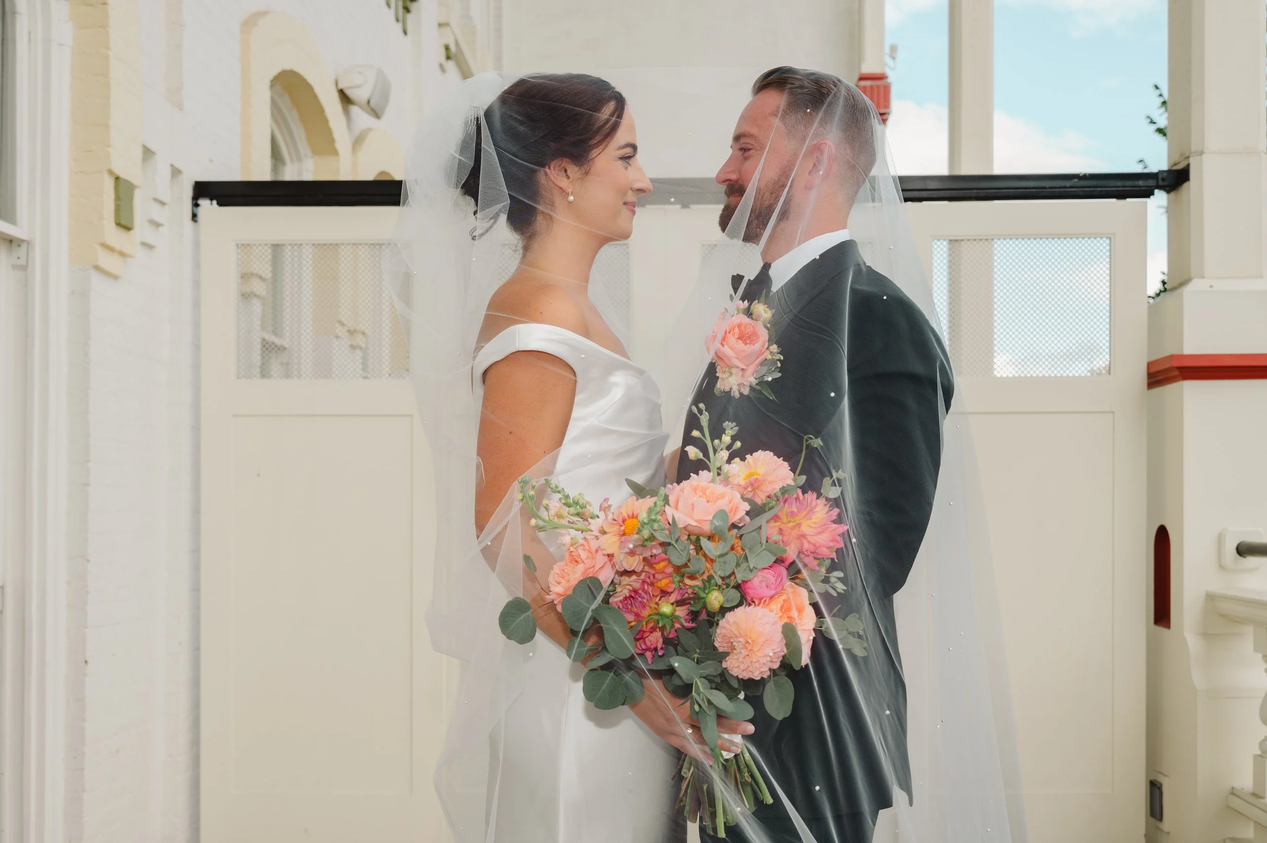 Bride and groom connect deeply under the veil, holding the bouquet together, following their emotional first look on the balcony at The Adelphi Saratoga Springs, New York. 