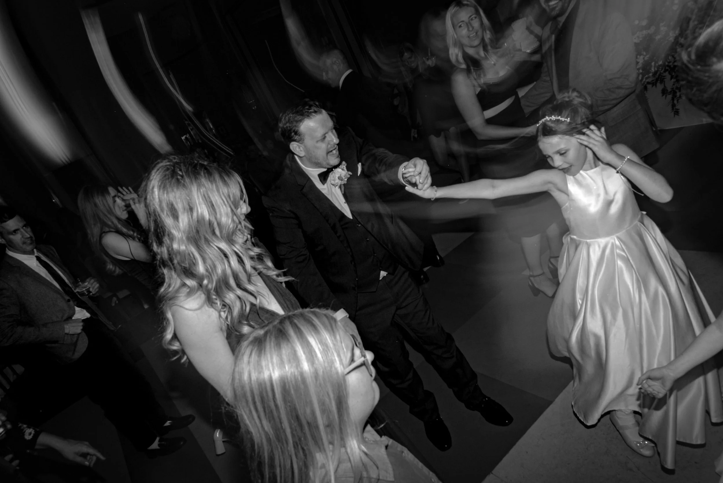 groom dances with daughter in a crowd of wedding guests on reception dance floor