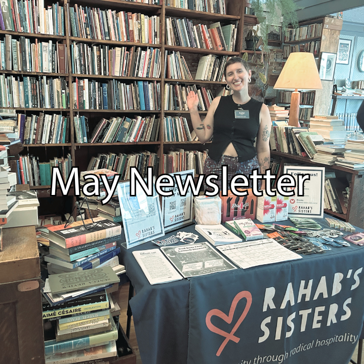Rahab's Sisters staff person, Kaylyn, stands behind a table decorated with flyers and information. Behind them is a wall of books.