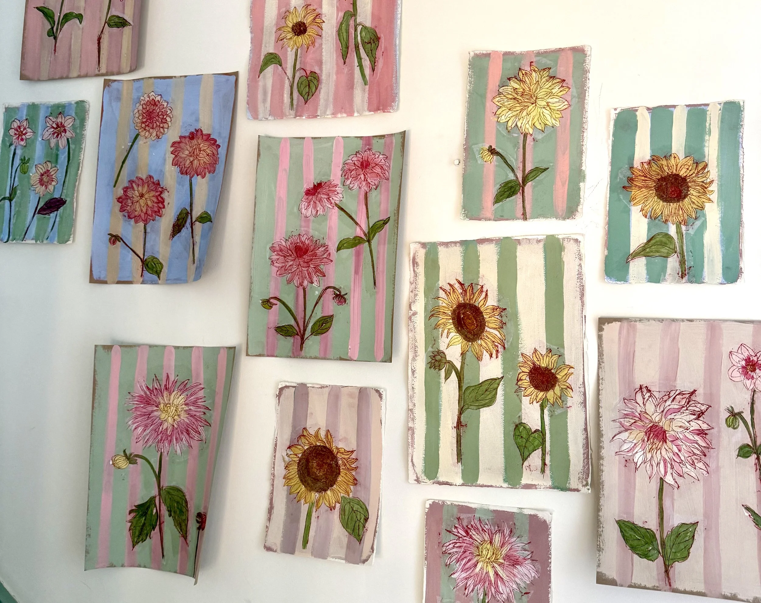 Close-up of three sheets of colorful, decorative paper with floral and geometric designs, layered on a wooden surface.