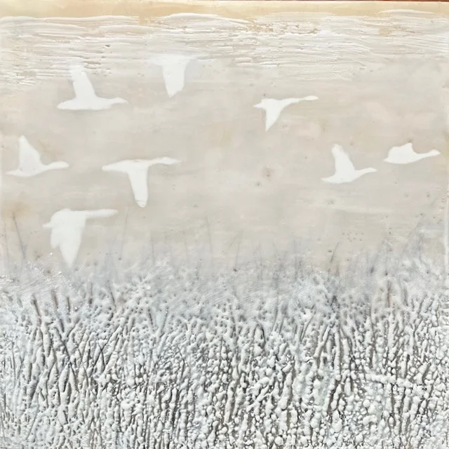 Wall with painted silhouettes of flying birds above textured grass or snow.