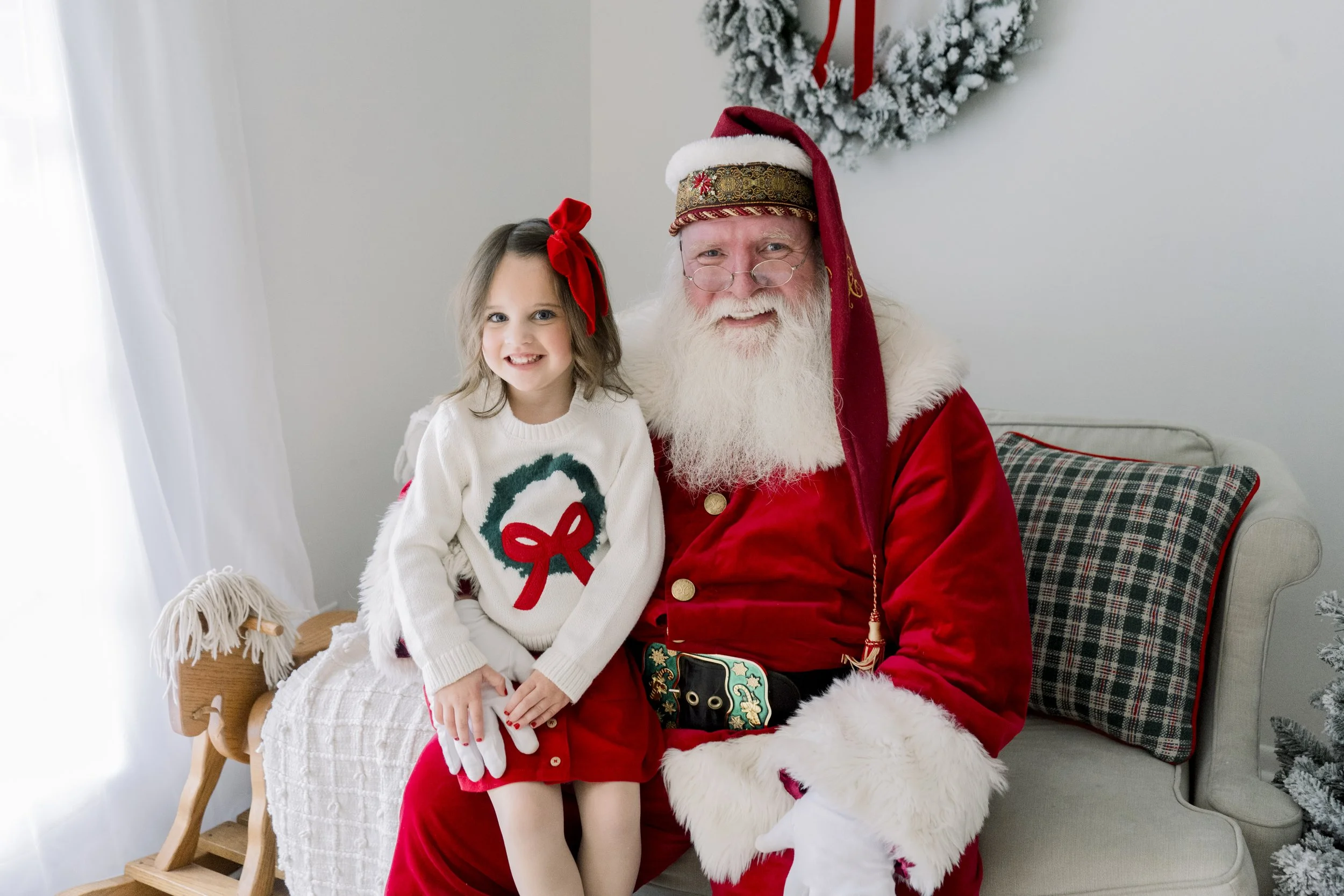 Girl sitting in Santa's lap for Christmas photos with Santa Sessions.