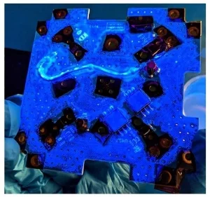 The -X panel during the conformal coating process under UV light