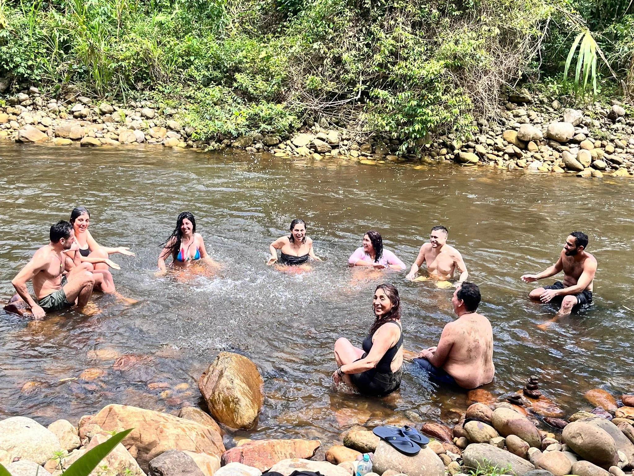 Grupo de personas nadando y disfrutando en un río rodeado de vegetación.