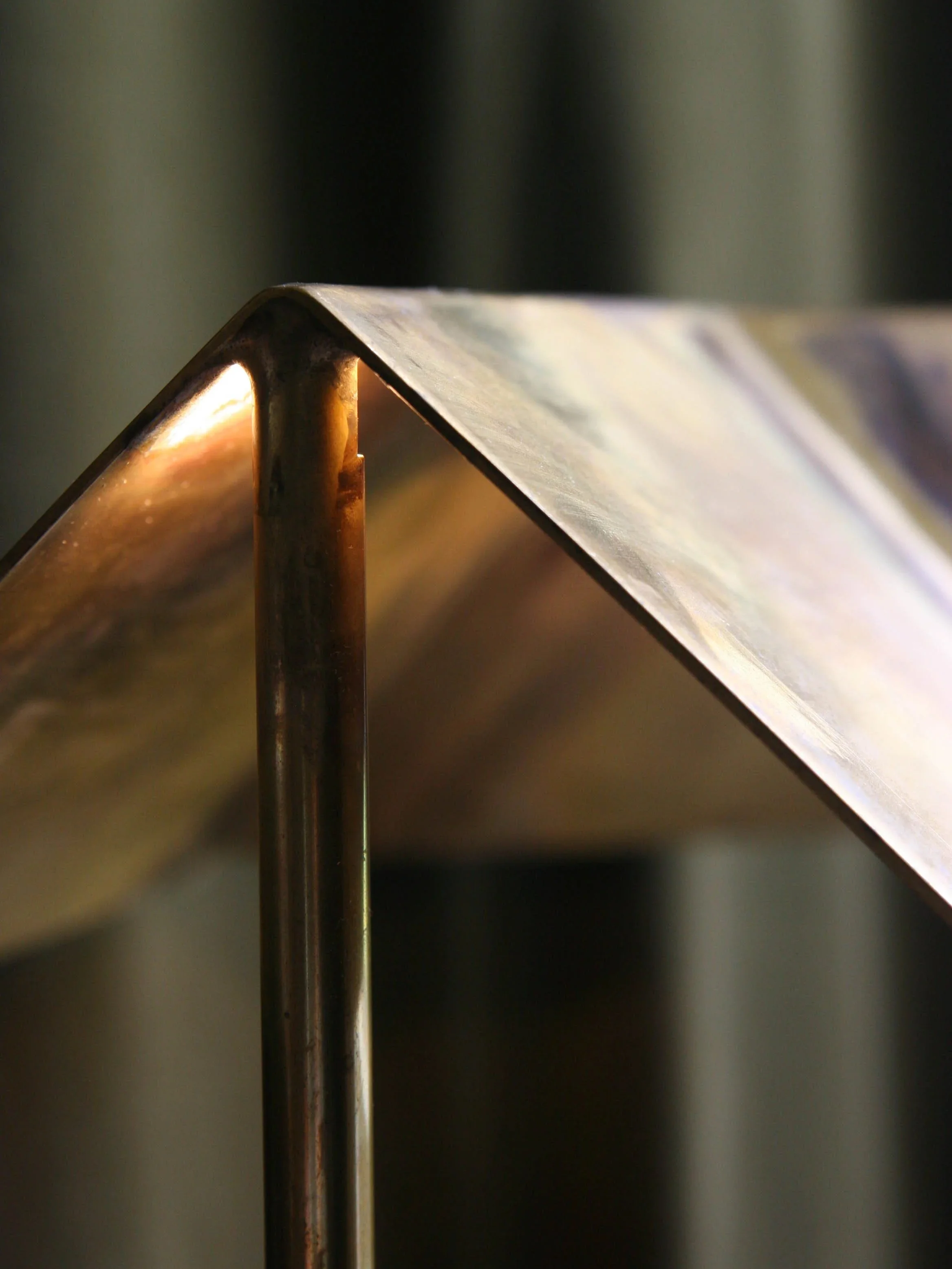 Close-up of a metal structure with a bent edge and a vertical support, with a blurred background.