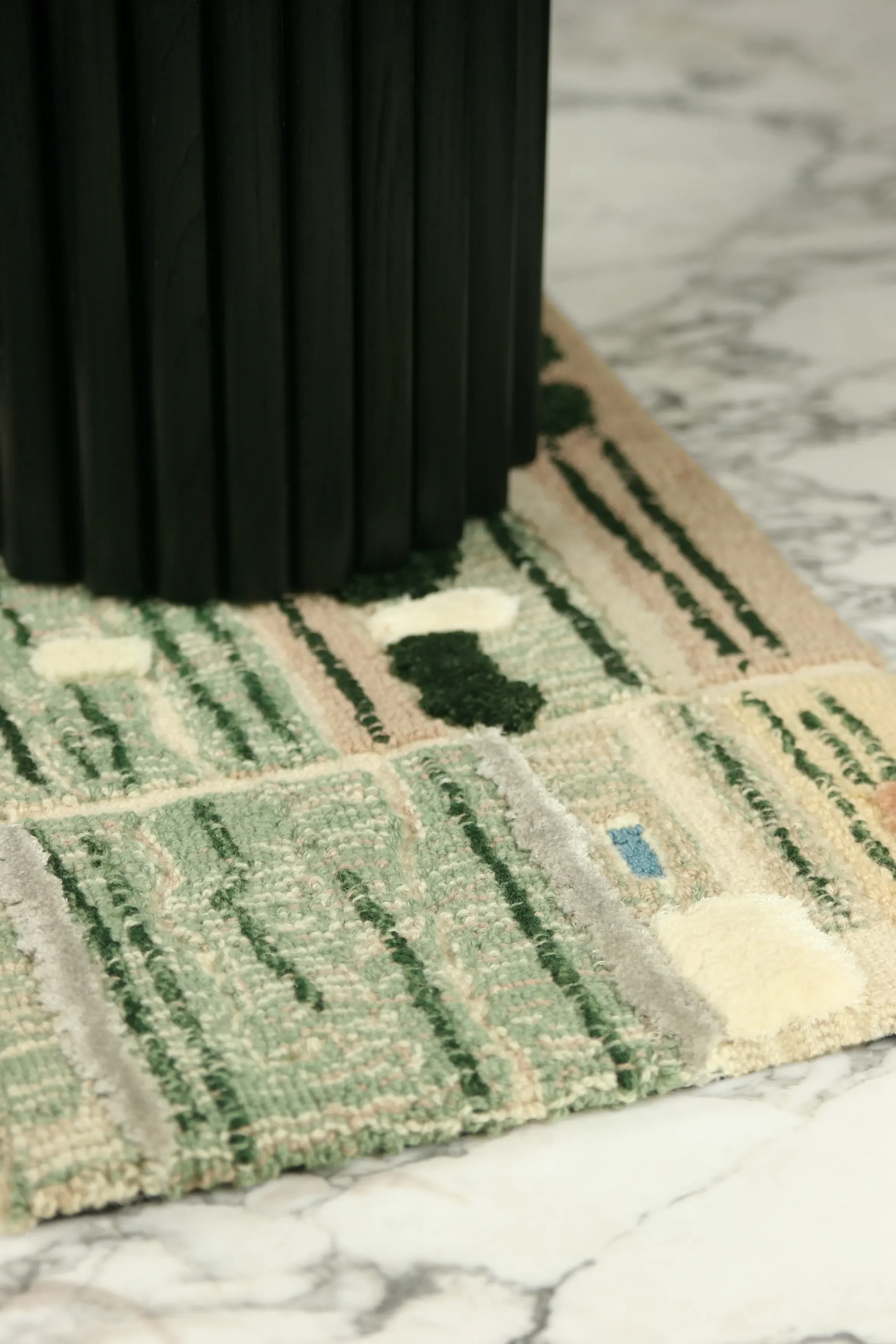 Detail view of EG-01 (Edge Occasional Side Table) base in blackened oak, made by Krzywda set on a Tangible Archives Epoch collection rug, designed by Edouard Sankowski, made in collaboration with Ateliers Pinton, showing loop pastels, green velvets