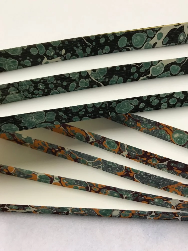 Dark green and orange marbled edges on notebook blocks.
