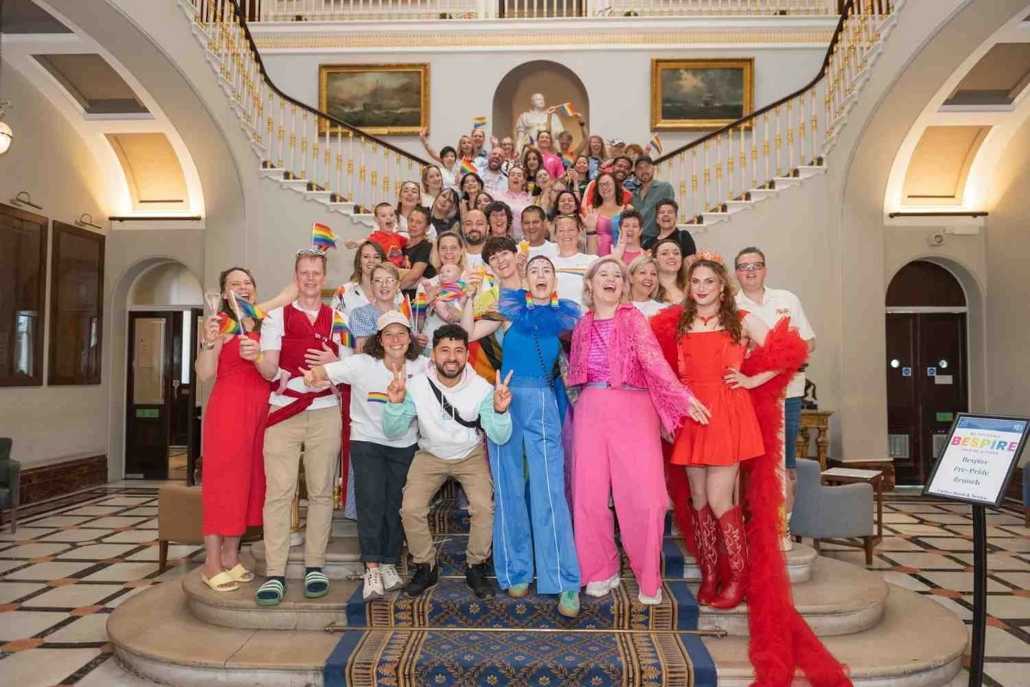 A group of people which attended Pride brunch standing at the main staircase of 116 Pall Mall