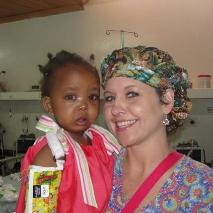 Arkansas children’s hospital nurse caring for Kenyan child wearing one our divas dressing darlings dresses. This mission was in partnership with arkansas children’s hospital and the nonprofit, change of face.