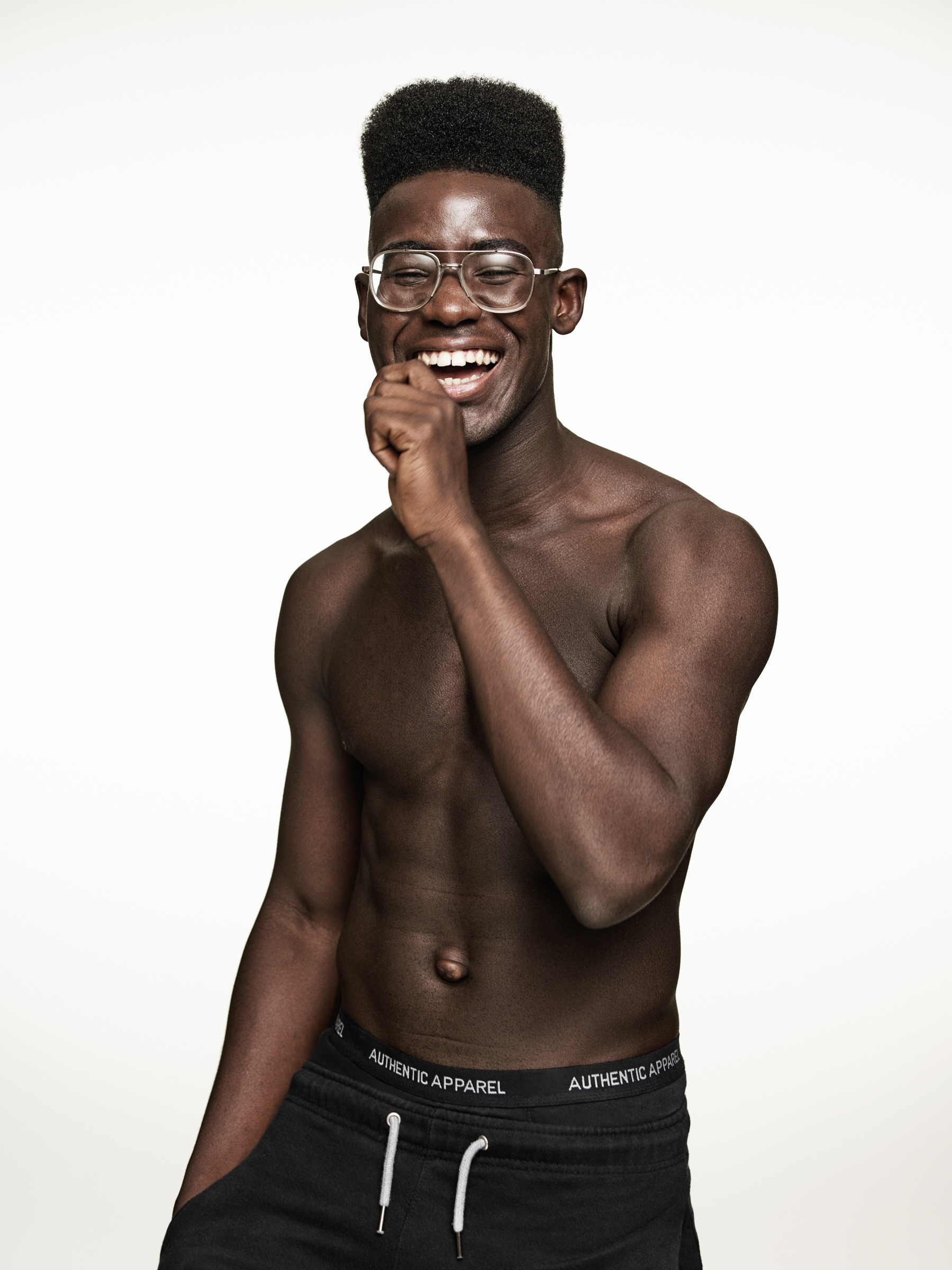 A black model with flat top hair and glasses smiling in the studio