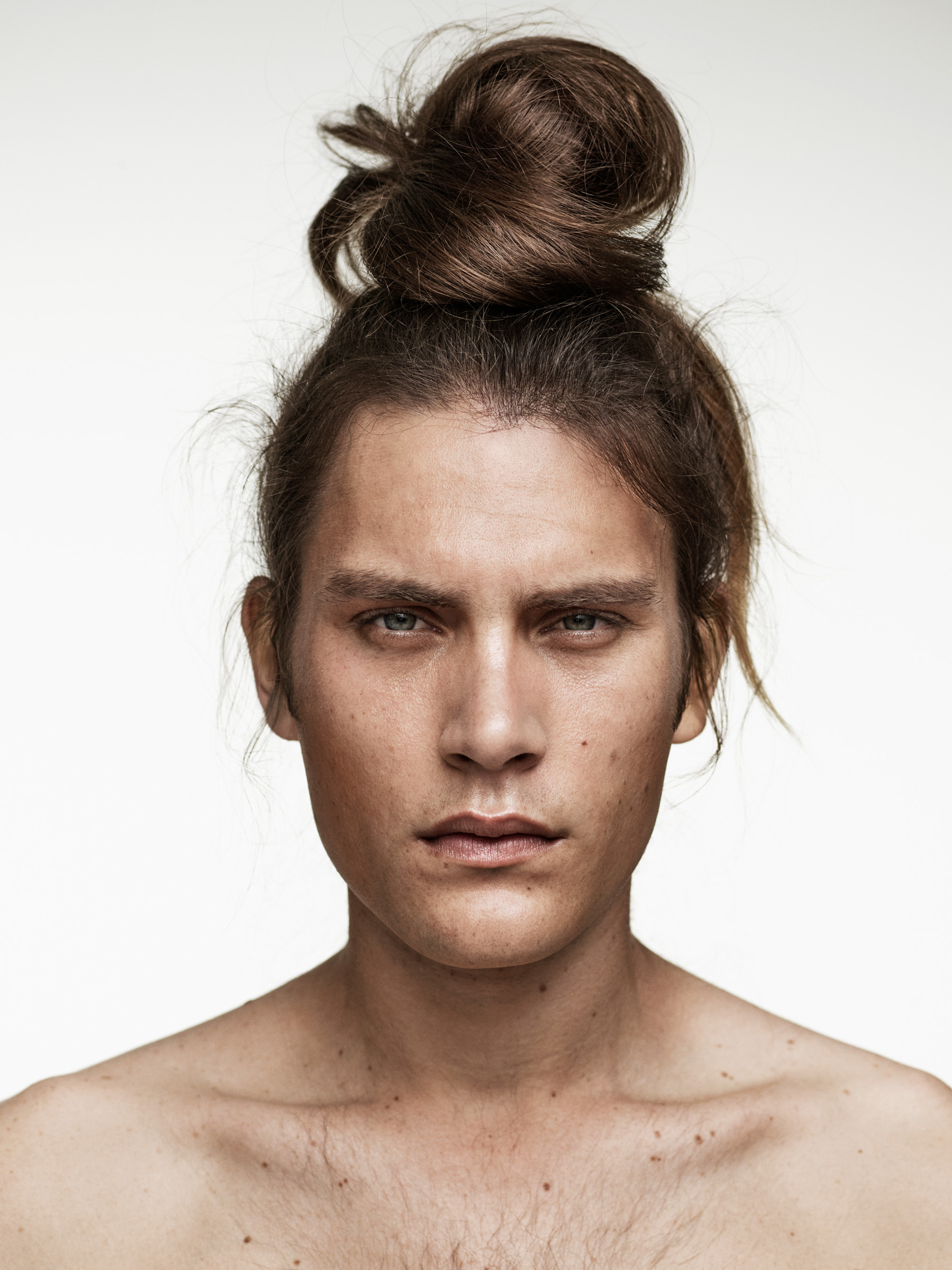 A male model with long blonde hair in a bun styled by Hooker and Young