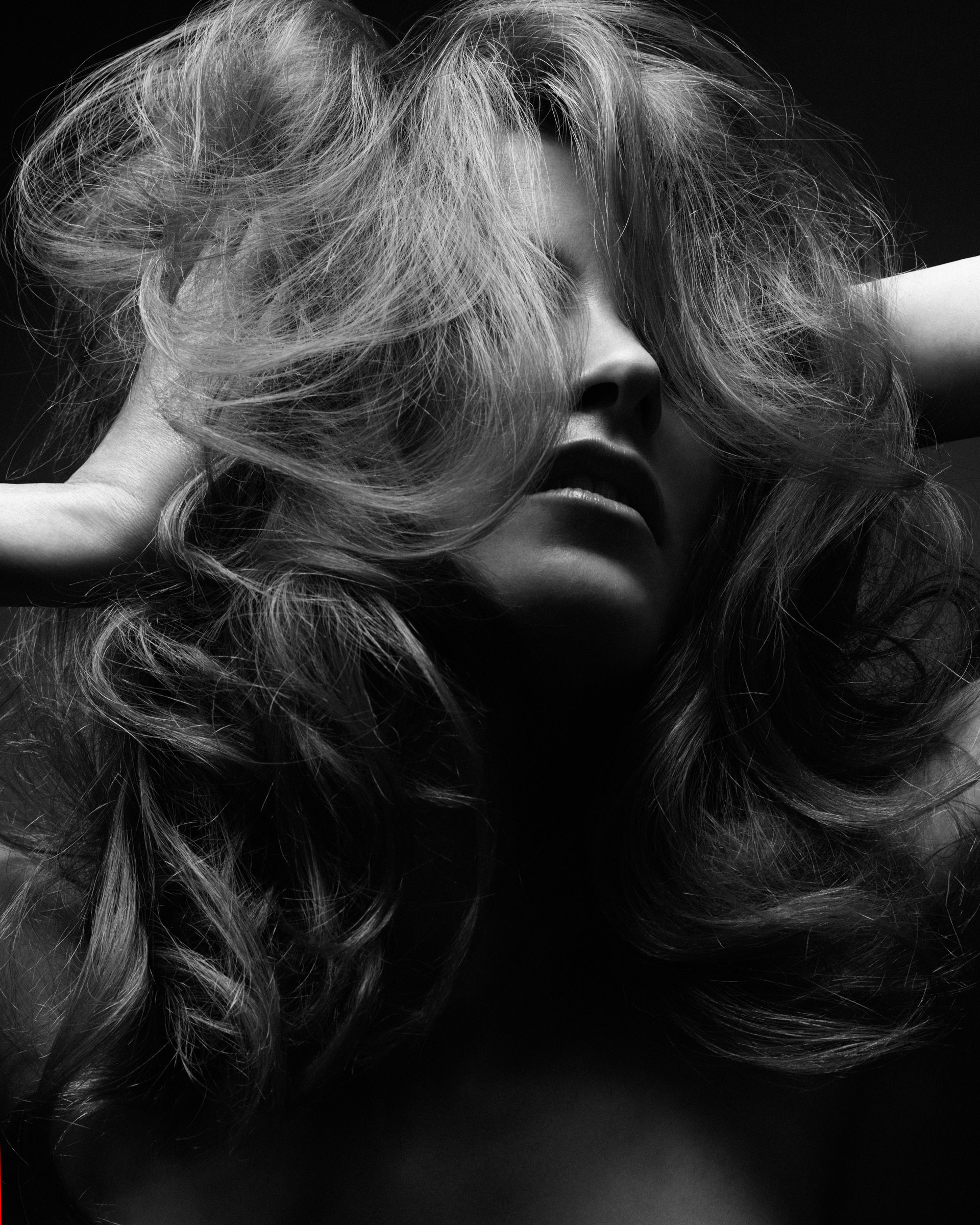 A female model with voluminous curly long hair in a studio