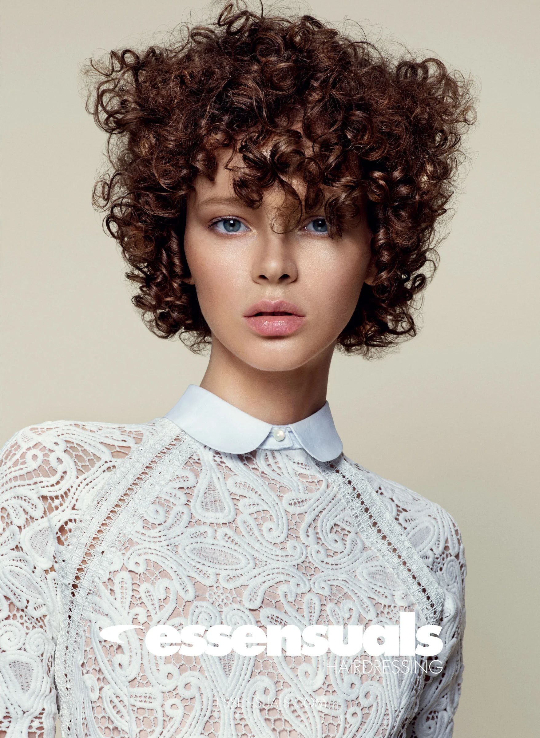 Woman with short curly brunette hair behind Essensuals logo