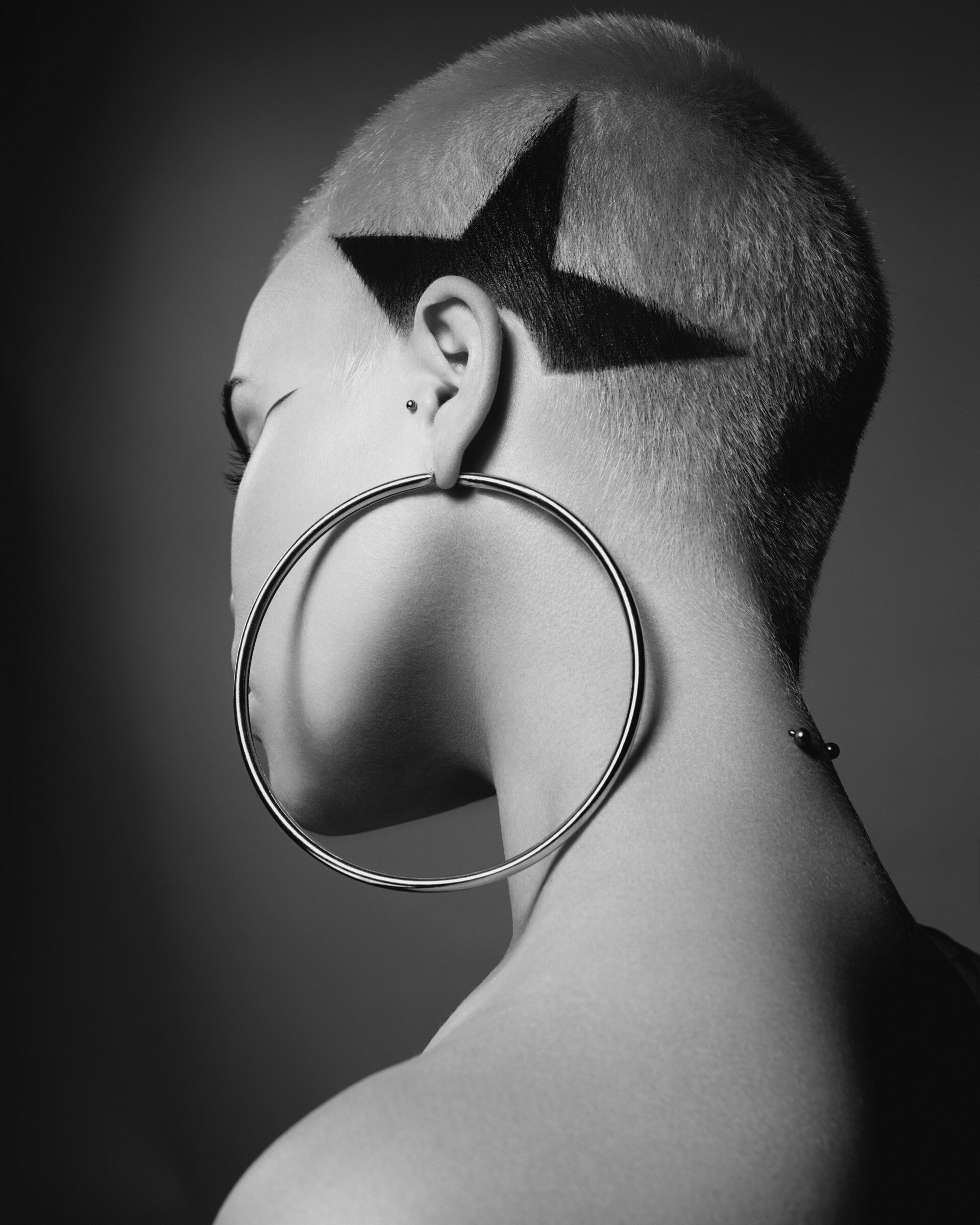 Black and white image of a woman with a star shaved into her hair