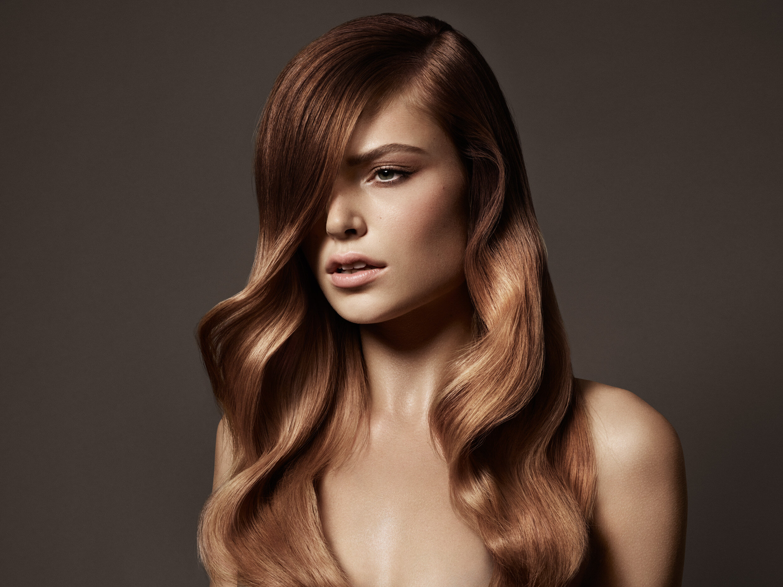 Woman in photography studio with curly strawberry blonde hair styled by Toni and Guy