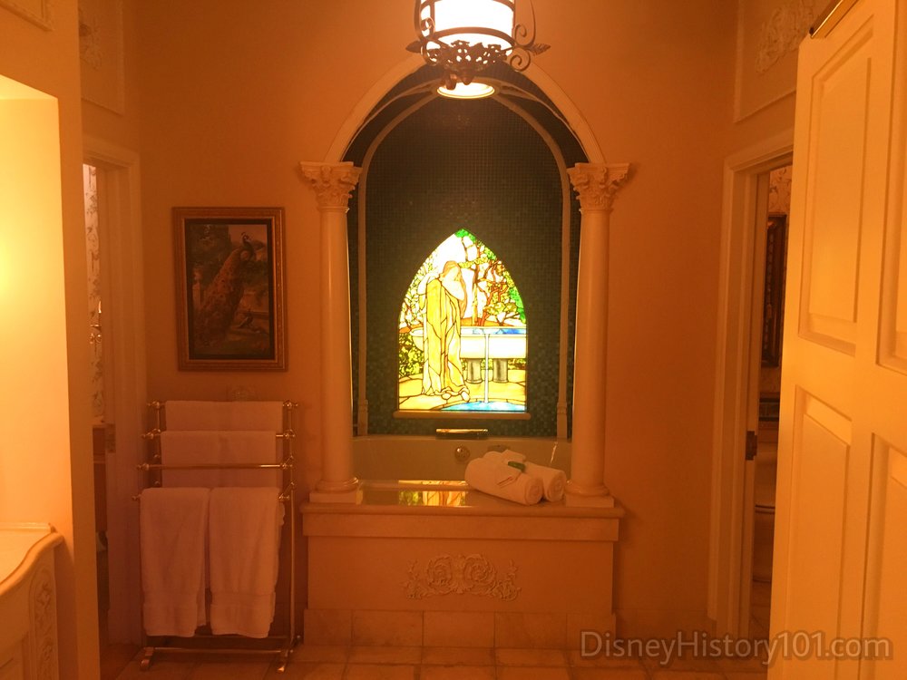 The bath is illuminated partially by a miniature exedra with faux stained glass inset.