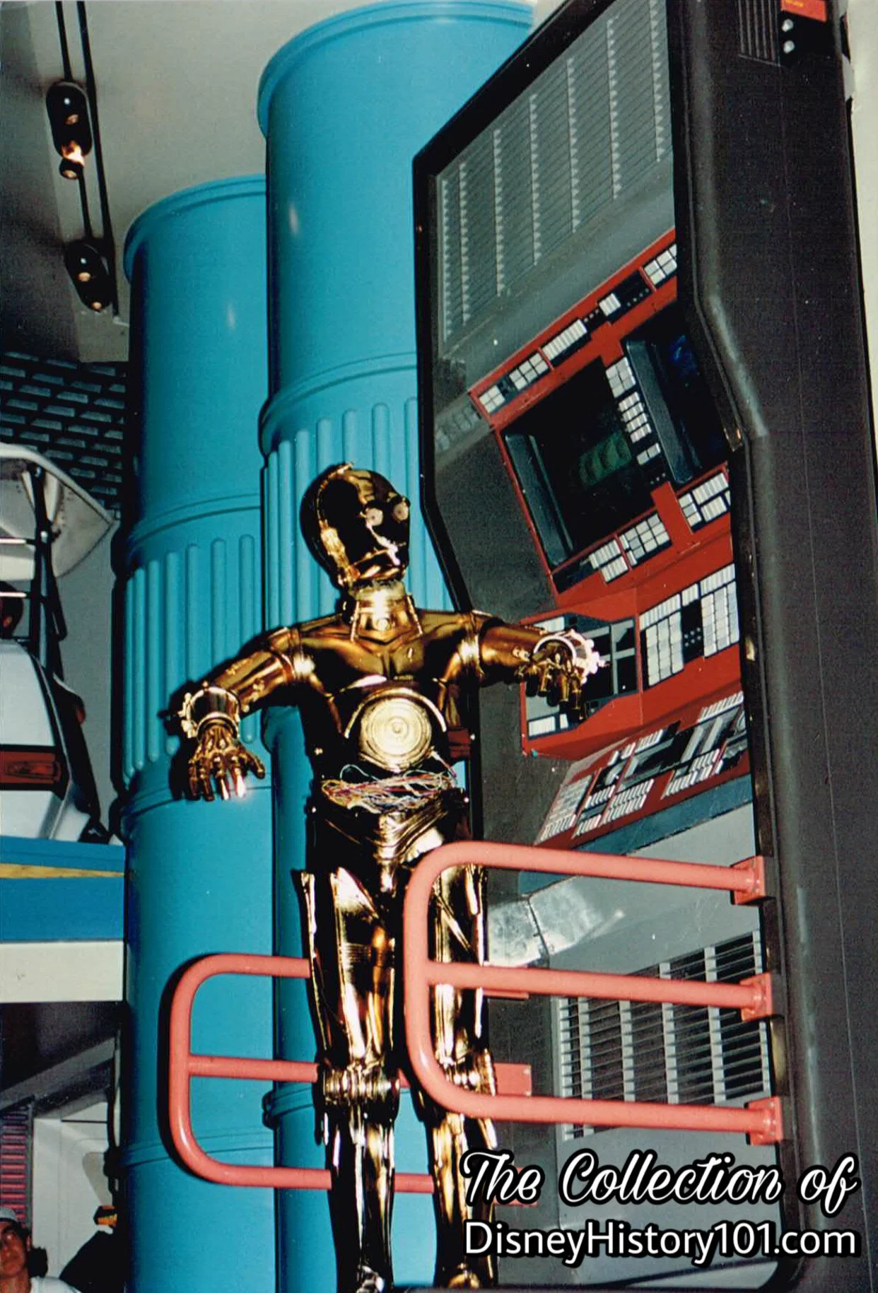 While Guests wait in an orderly fashion (queue) to board Star Tours, the animated C-3PO runs diagnostics on a StarSpeeder 3000 transport craft in The Spaceport.