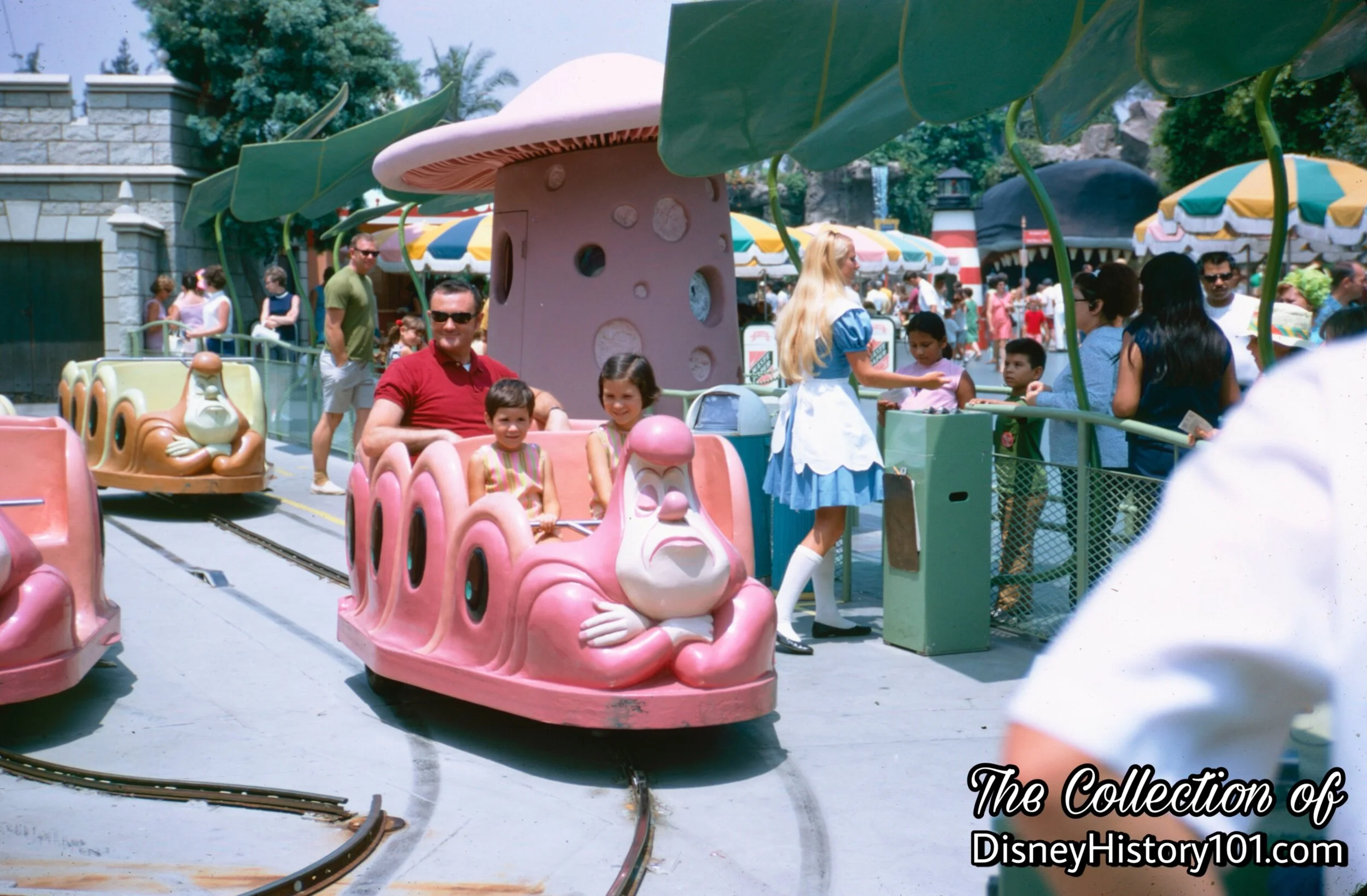 The Caterpillar-inspired vehicles of Alice in Wonderland and Hostess welcoming Guests in the Guest Control queue.