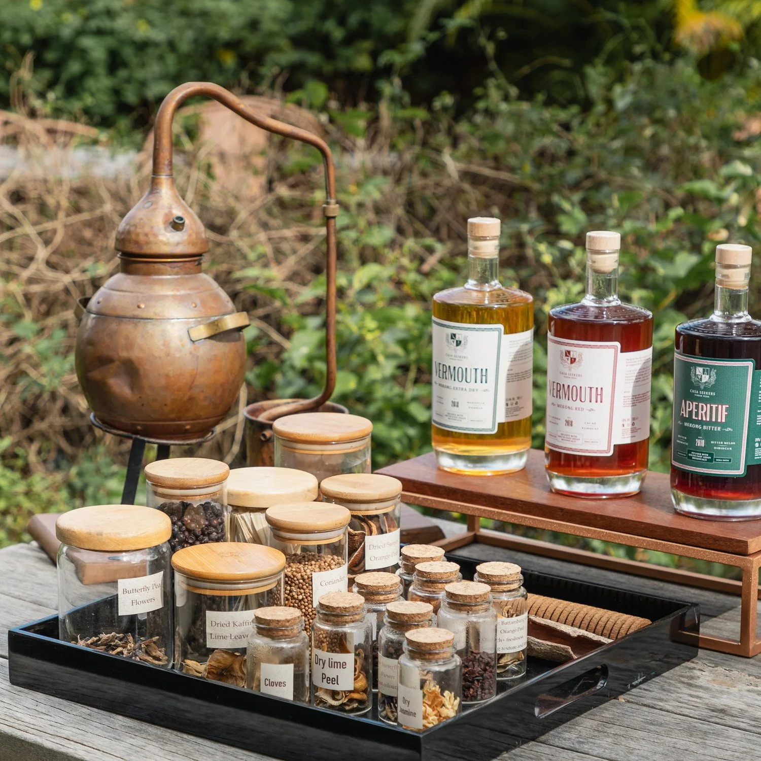 Copper pot still and Casa Seekers bottles set out with botanicals at the distillery
