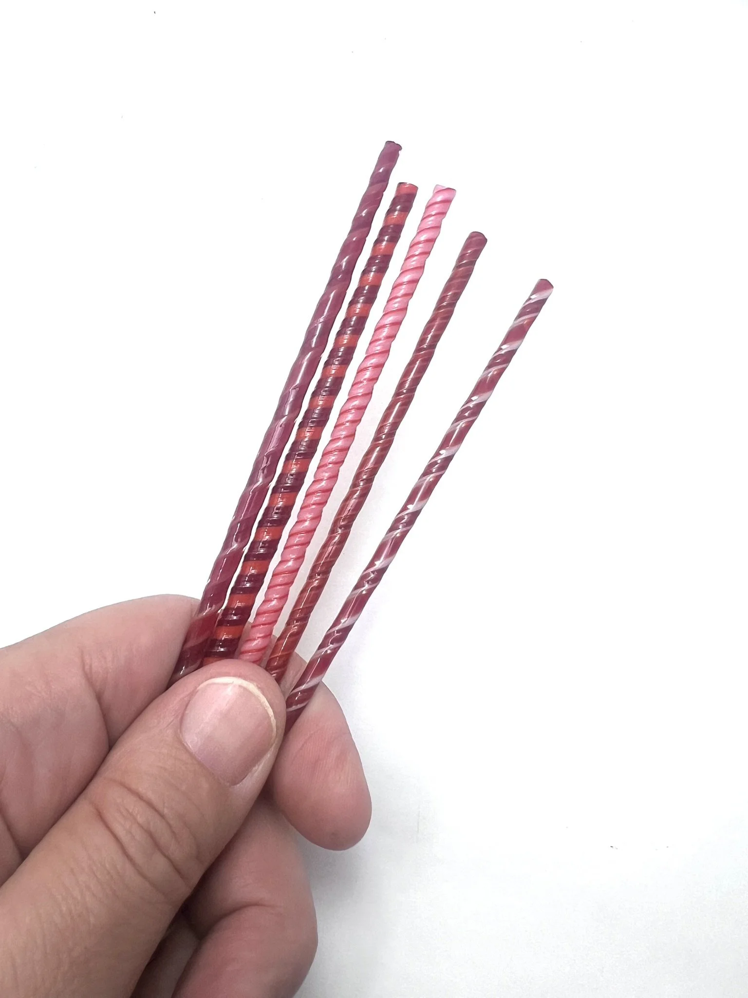 a hand holding 5 red glass twisties