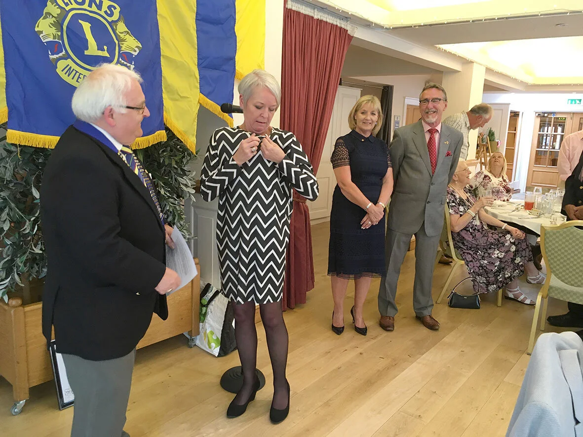 New Lion Dulcie McDonald pinning on her Lions insignia after it’s presentation by Lion President Chris Eglington, watched by Dulcie’s sponsors for membership - Lions Sharon Page and Keith Moore
