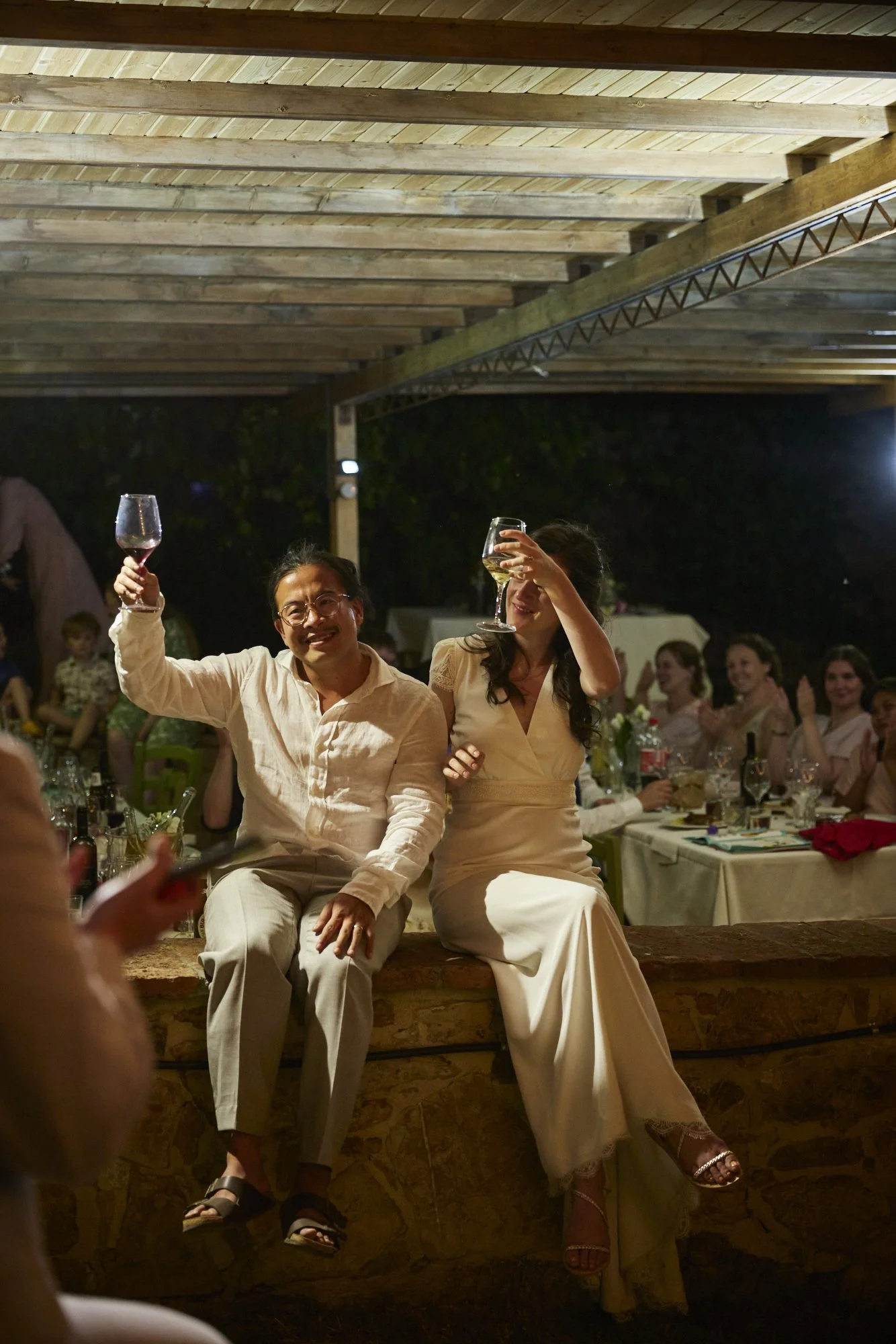 People enjoying a toast at an indoor celebration with a wooden ceiling and decorated table.