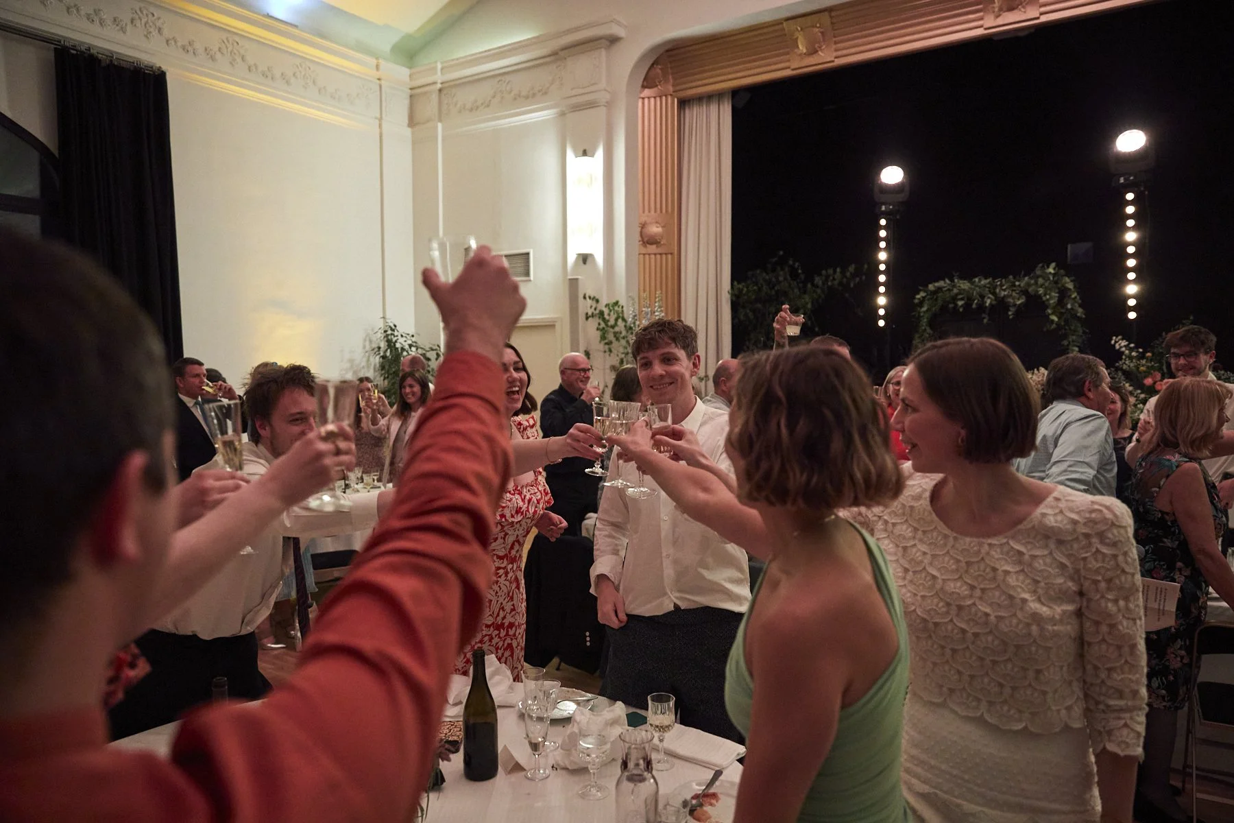 People celebrating with drinks at a formal event or party, raising glasses in a toast inside an elegant venue.