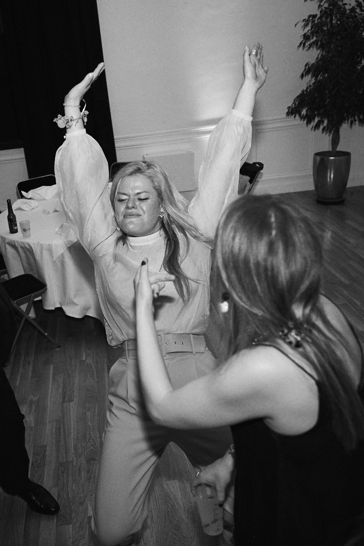 Woman dancing with her hands raised and a joyful expression at an indoor event.