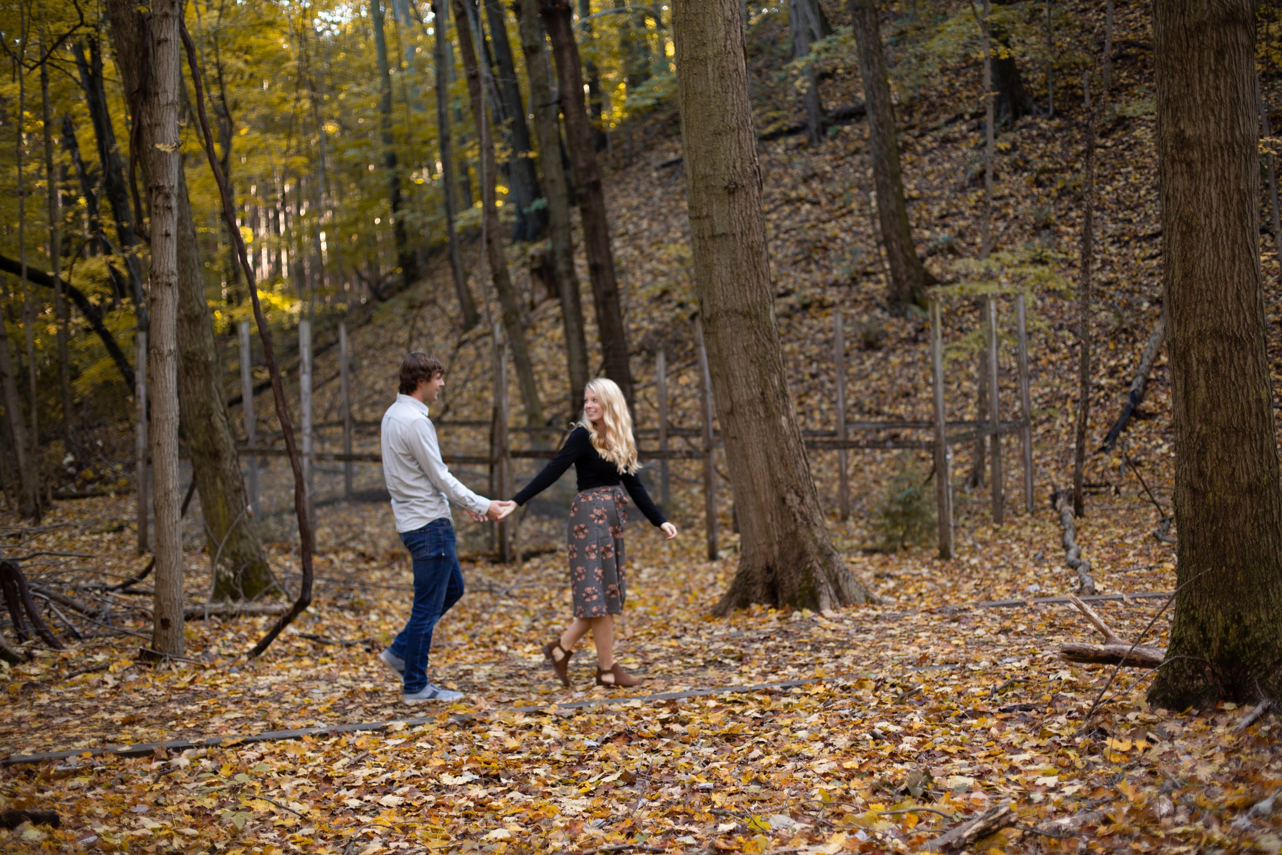 A+couple+walking+through+fall+leaves.jpeg