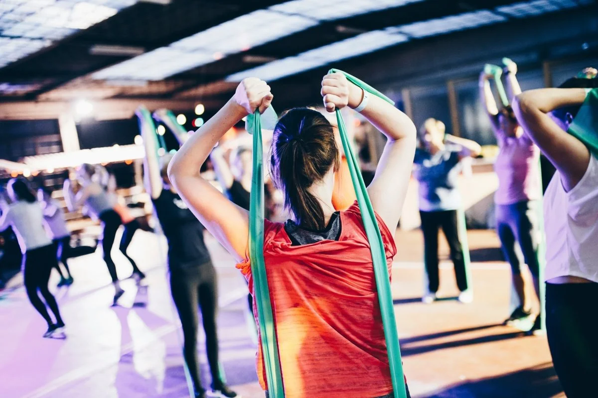 Blurred focus photo of woman in workout class with exercise bands, representing someone asking what is exercise bulimia?