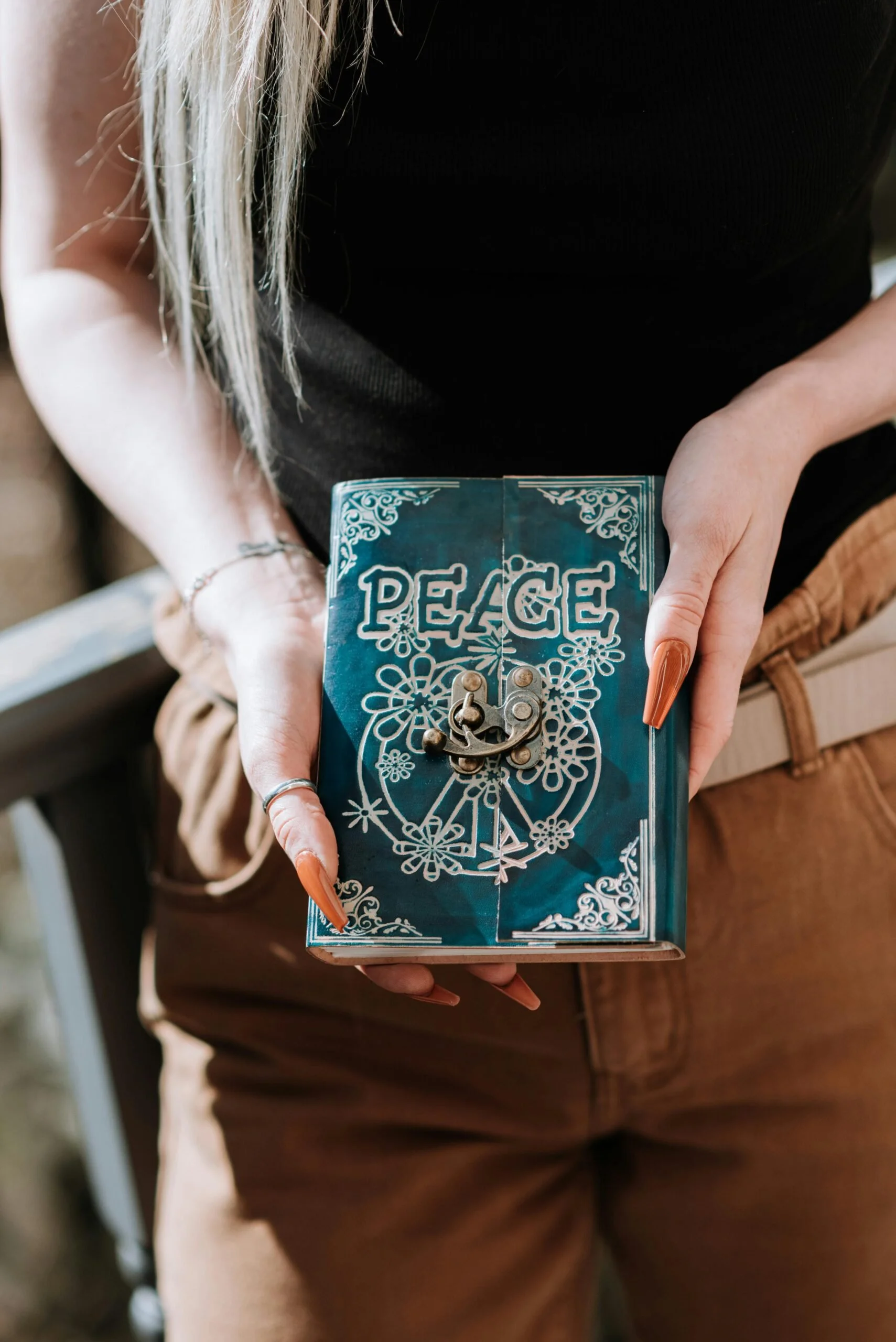A woman holding a journal that has a stylized "peace" on the cover, showing a healthy coping skill learned through DBT therapy