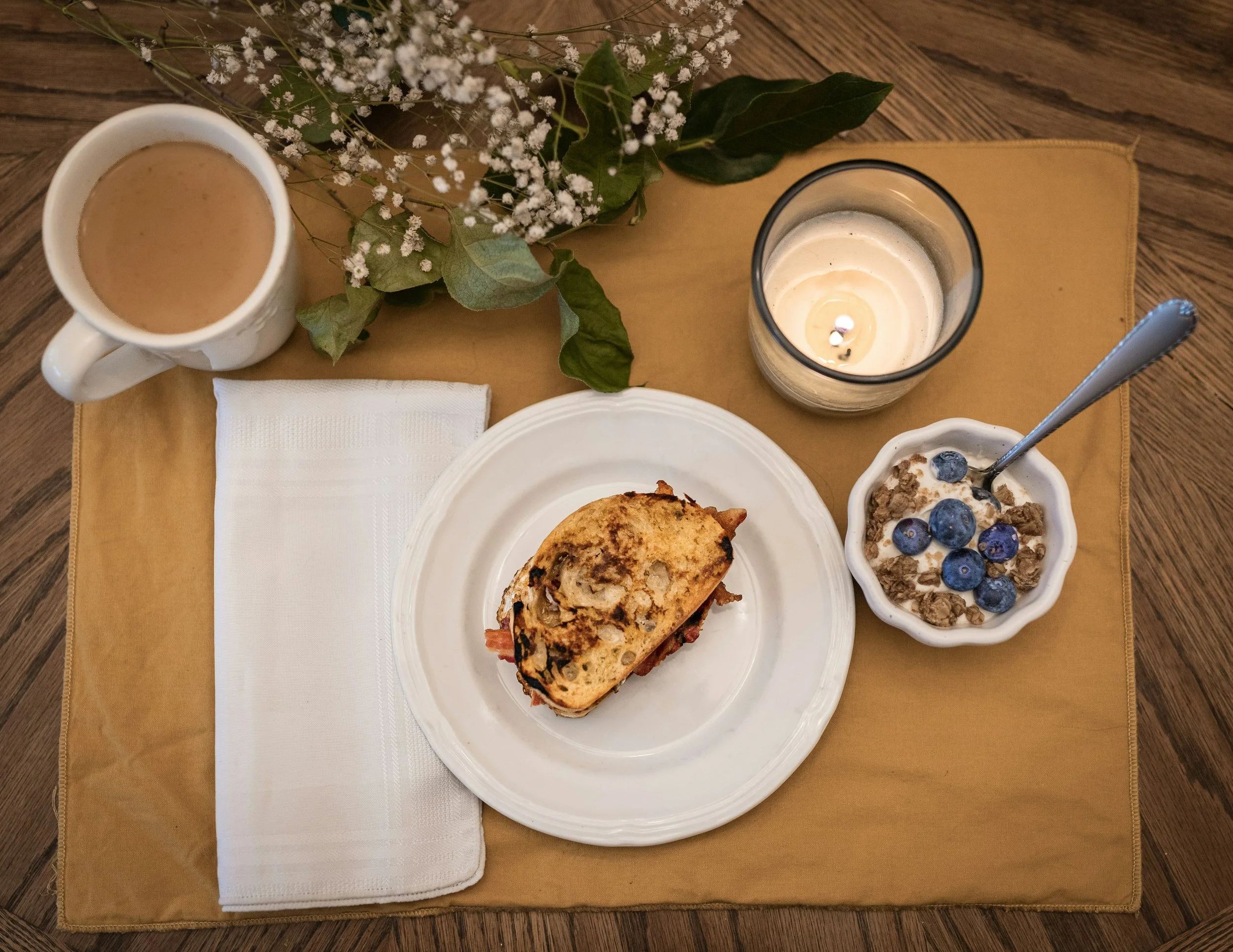 Balanced meal with coffee, yogurt, fruit, and sandwich in a calm dining environment, representing mindful eating and sustainable eating disorder recovery through intentional nourishment.