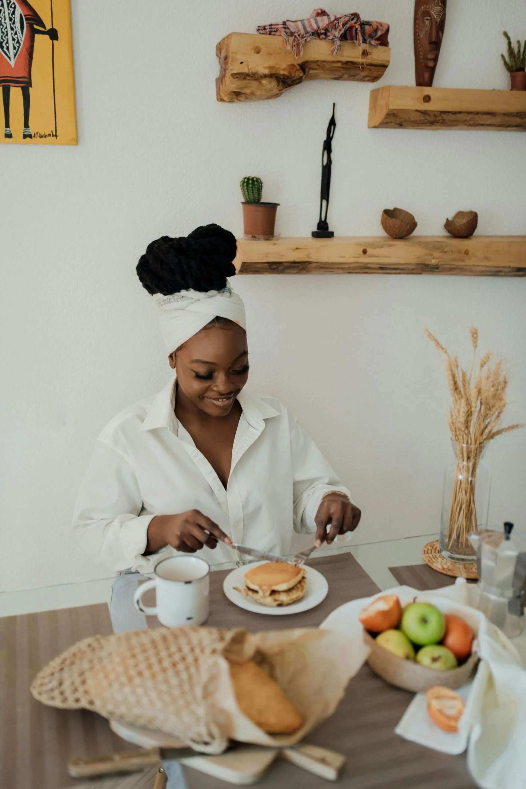 Woman smiling as she prepares to eat pancakes at a cozy breakfast table—representing mindful eating, morning rituals, and restoring a peaceful relationship with food.