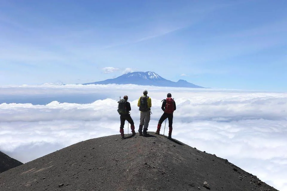 874292-three-hikers-are-looking-at-mount-kilimanjaro-from-the-rocky-ridge-of-mount-meru.jpg