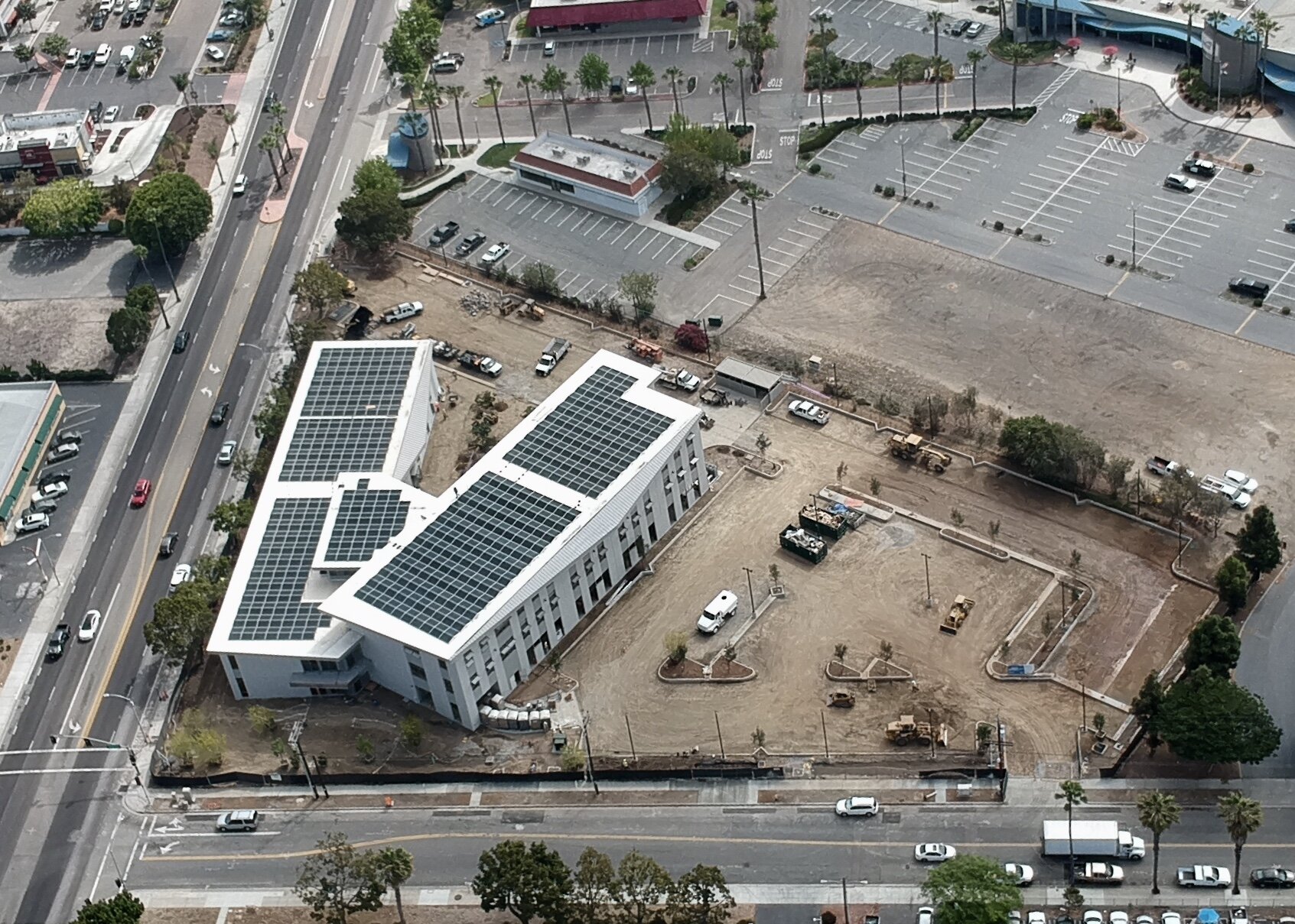  Aerial view of two buildings with a dirt parking lot. 
