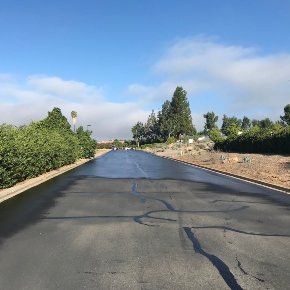  A road with crackfill applied to the cracks. It is partially covered in seal coat.  