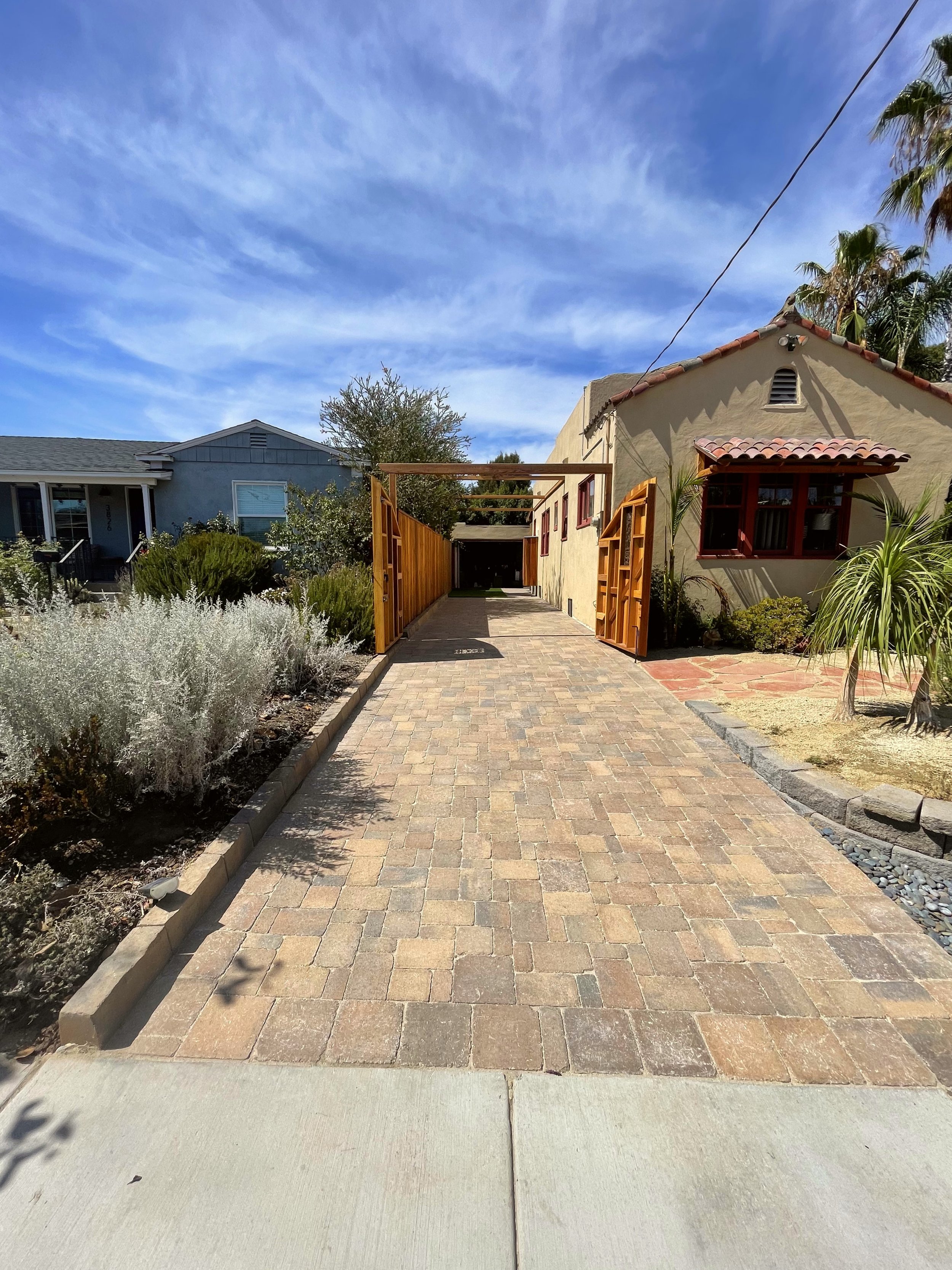  A long residential driveway with tan colored pavers 