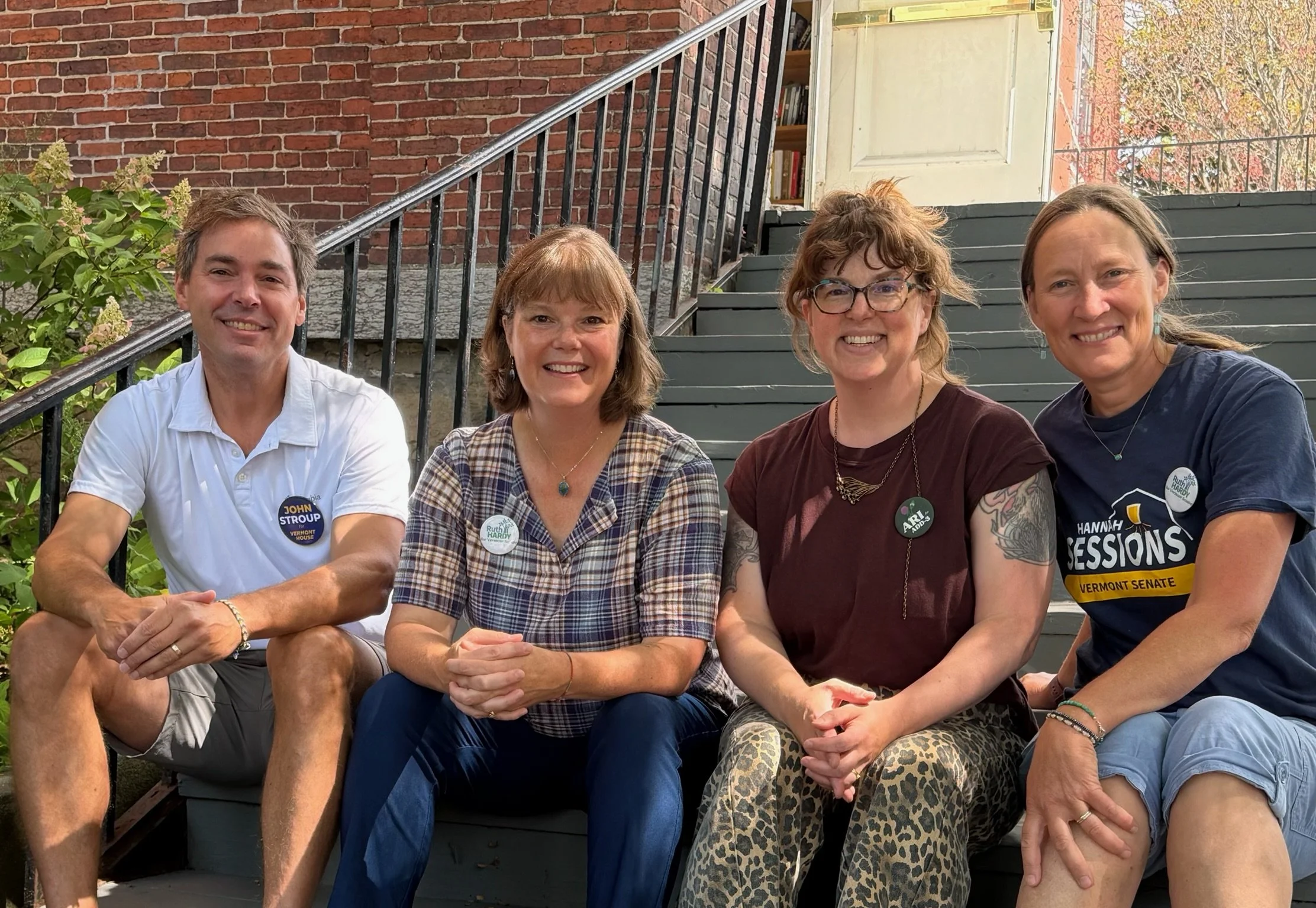 John Stroup, Ruth Hardy, Ariel Bolles and Hannah Sessions sit on stairs and smile