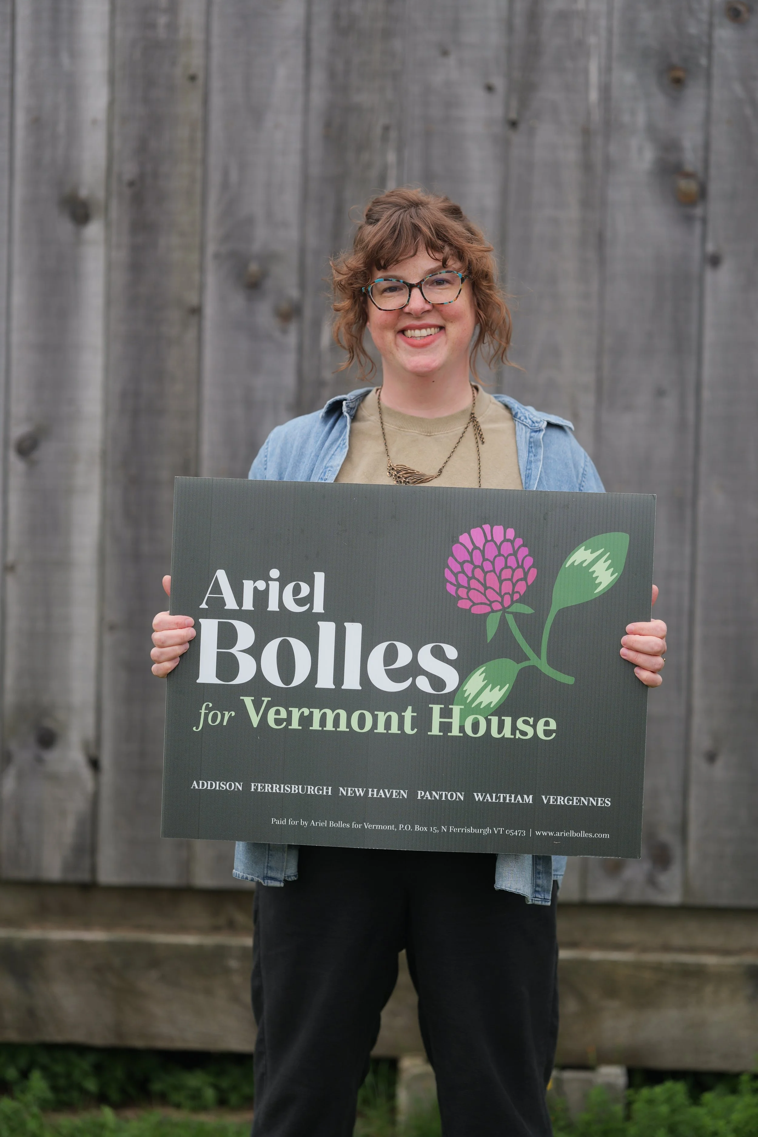 Ariel Bolles holds a campaign yard sign that says "Ariel Bolles for Vermont House, Addison Ferrisburgh, New Haven, Panton, Waltham, Vergennes"