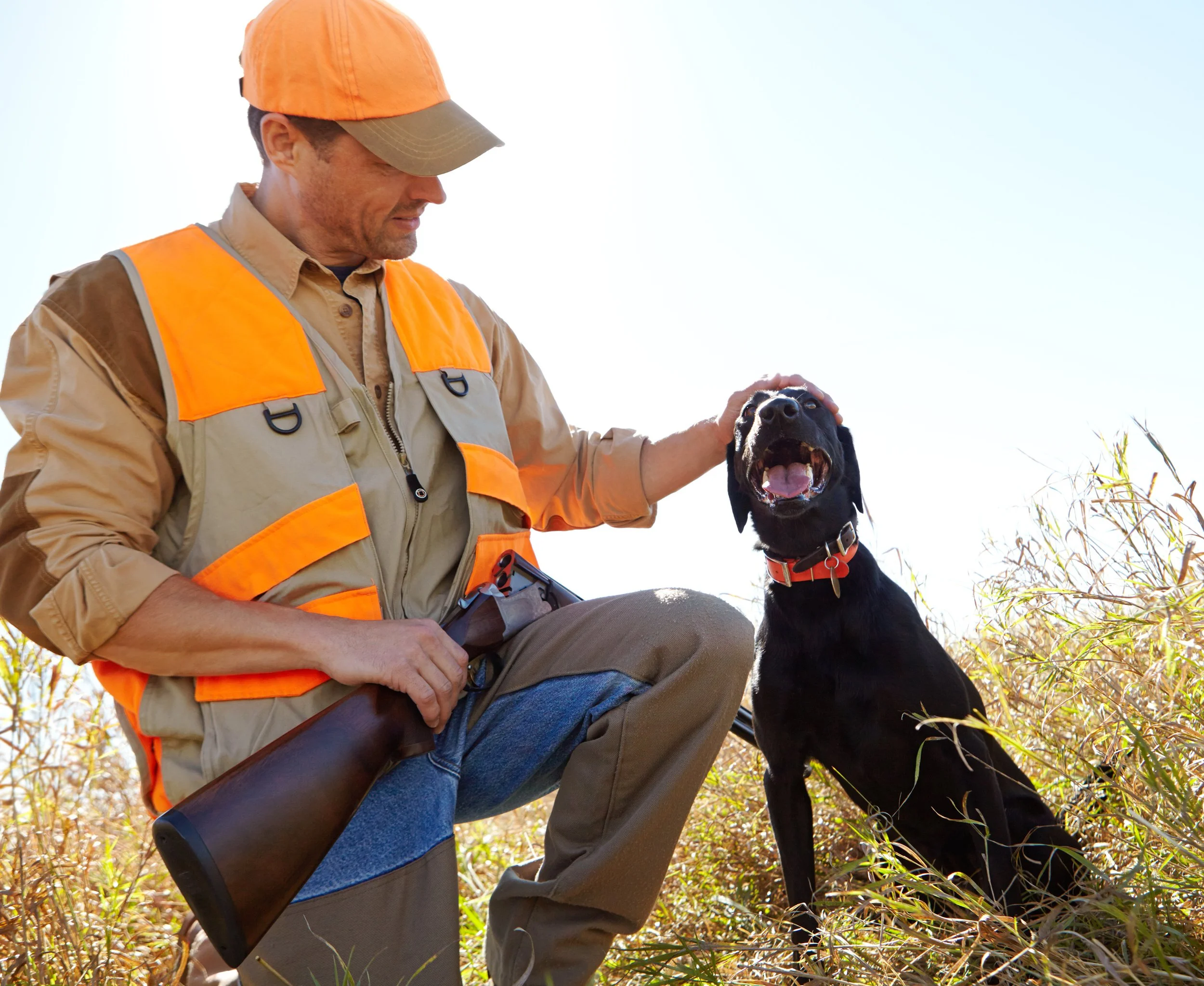 Hunter petting his dog in a field